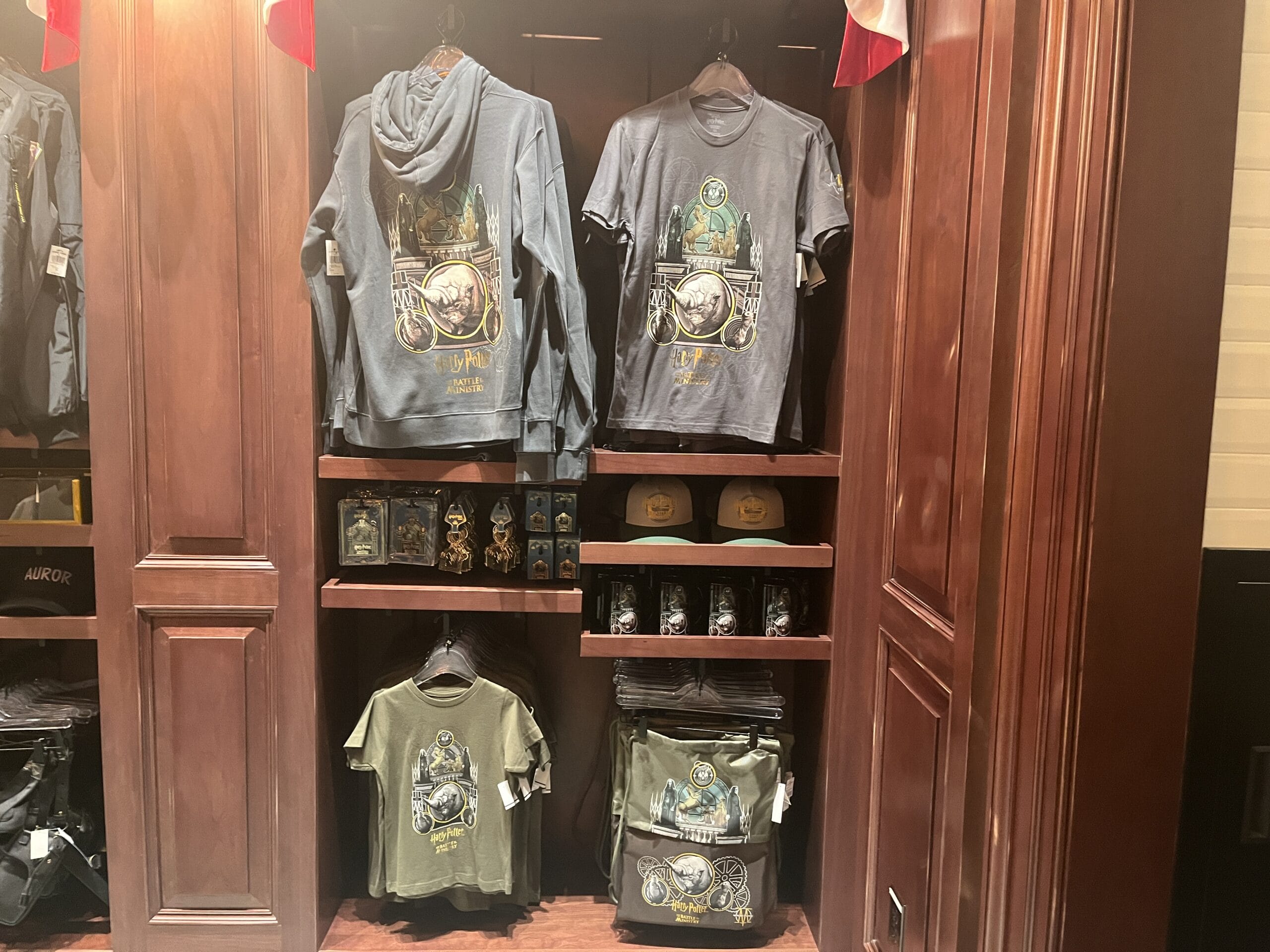 Dark wood shelves display Epic Universe hoodies, hats, mugs, and more Wizarding World of Harry Potter merchandise.