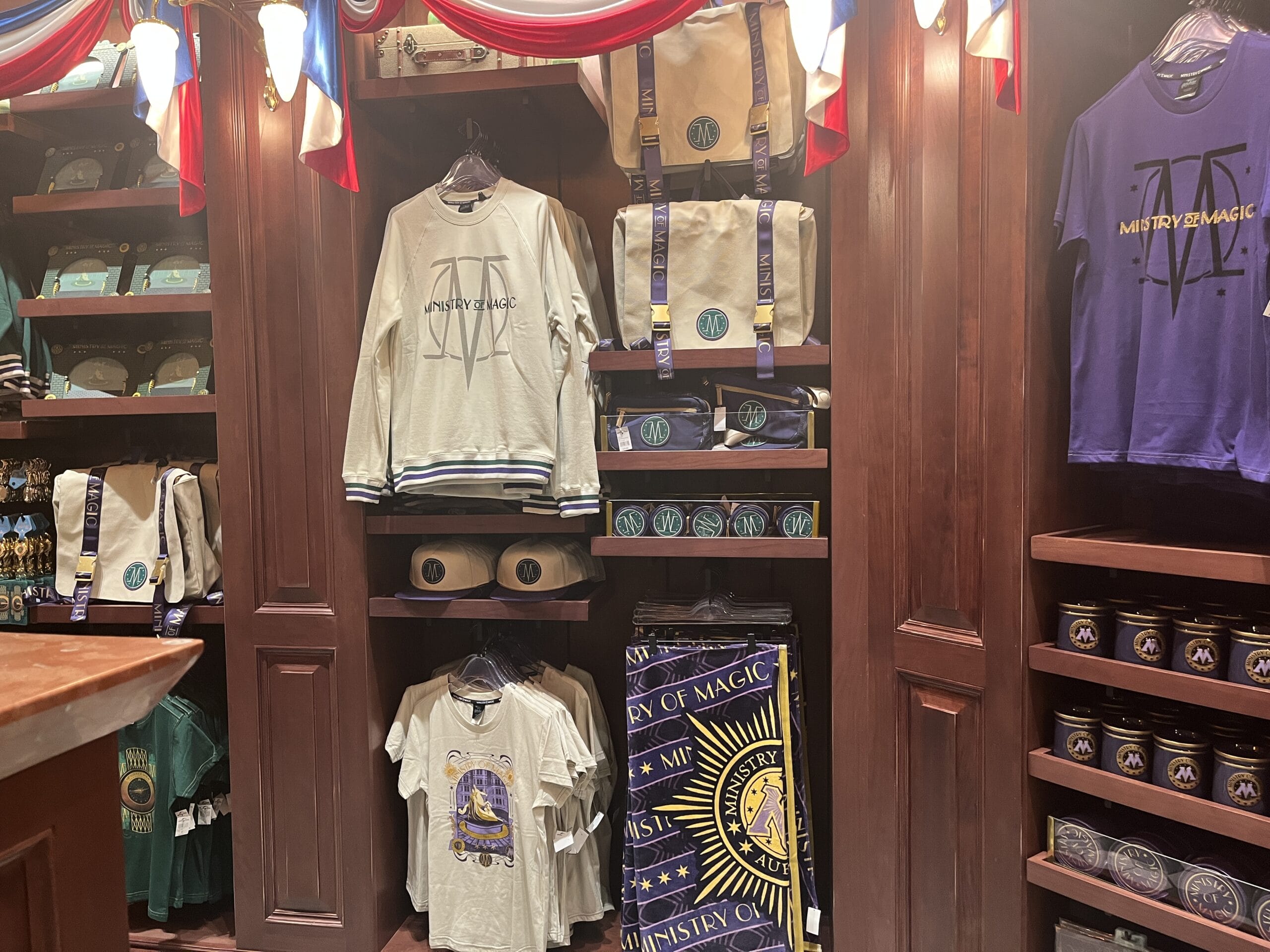 Shelves display Wizarding World of Harry Potter merchandise in a wooden shop with red and blue drapes at Epic Universe.