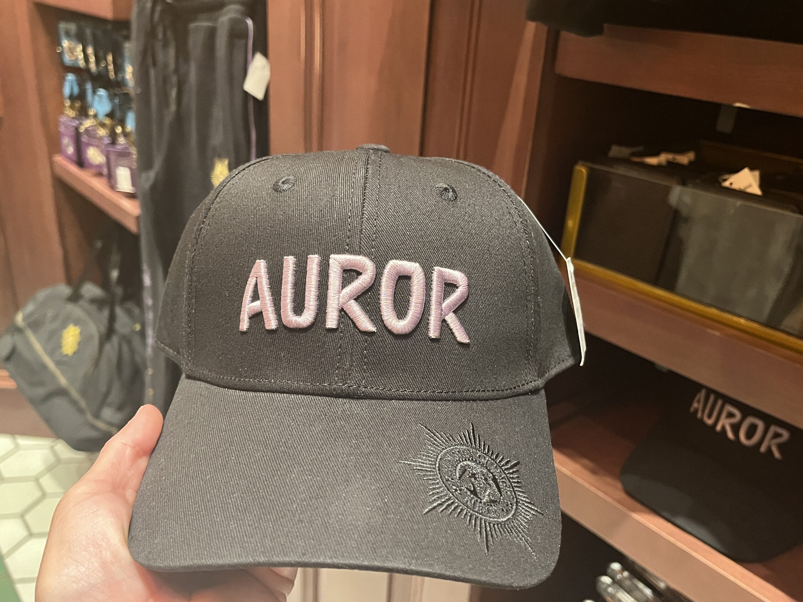 A black baseball cap with "AUROR" in pink and a small emblem—perfect Wizarding World of Harry Potter merchandise.