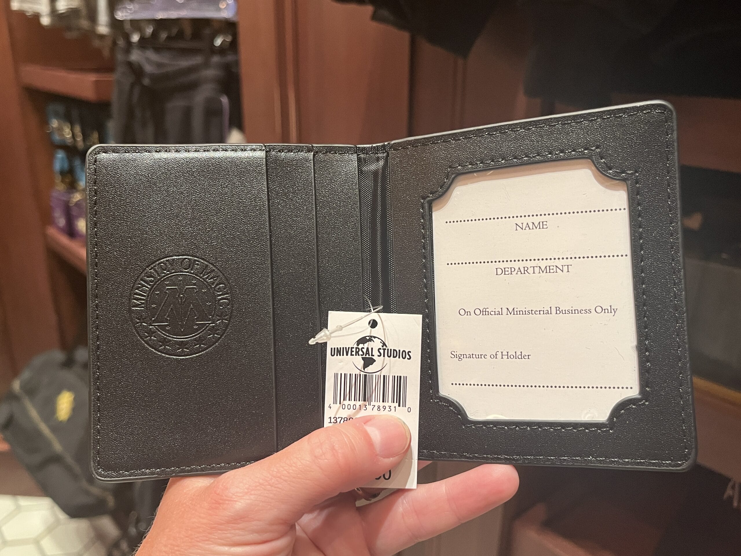 A hand holds a black wallet with a Ministry of Magic badge—unique Harry Potter merchandise at Universal Studios.
