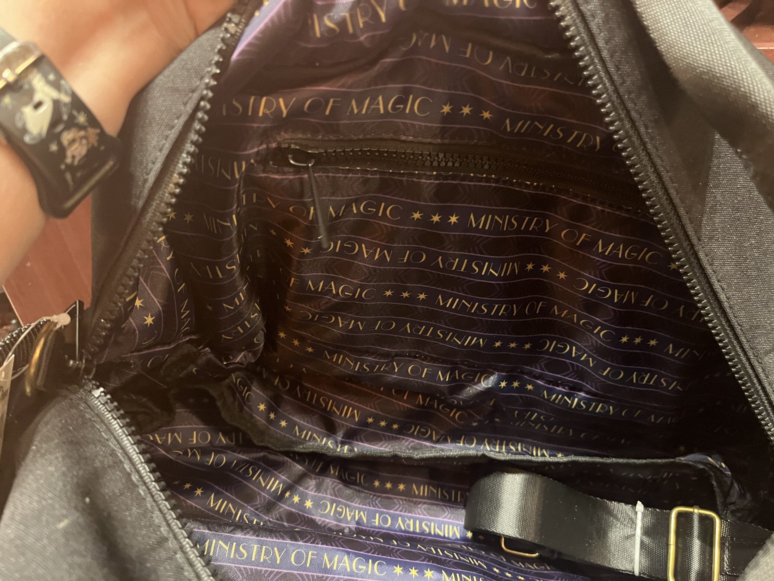 Open black bag with purple lining, gold "Ministry of Magic" print—must-have Wizarding World merchandise.