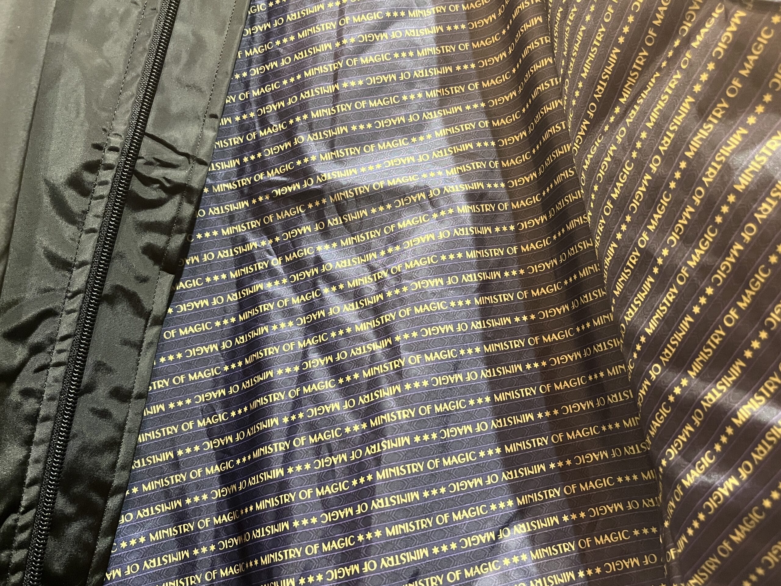 Black jacket lining with gold "MINISTRY OF MAGIC" text—exclusive Wizarding World of Harry Potter merchandise.
