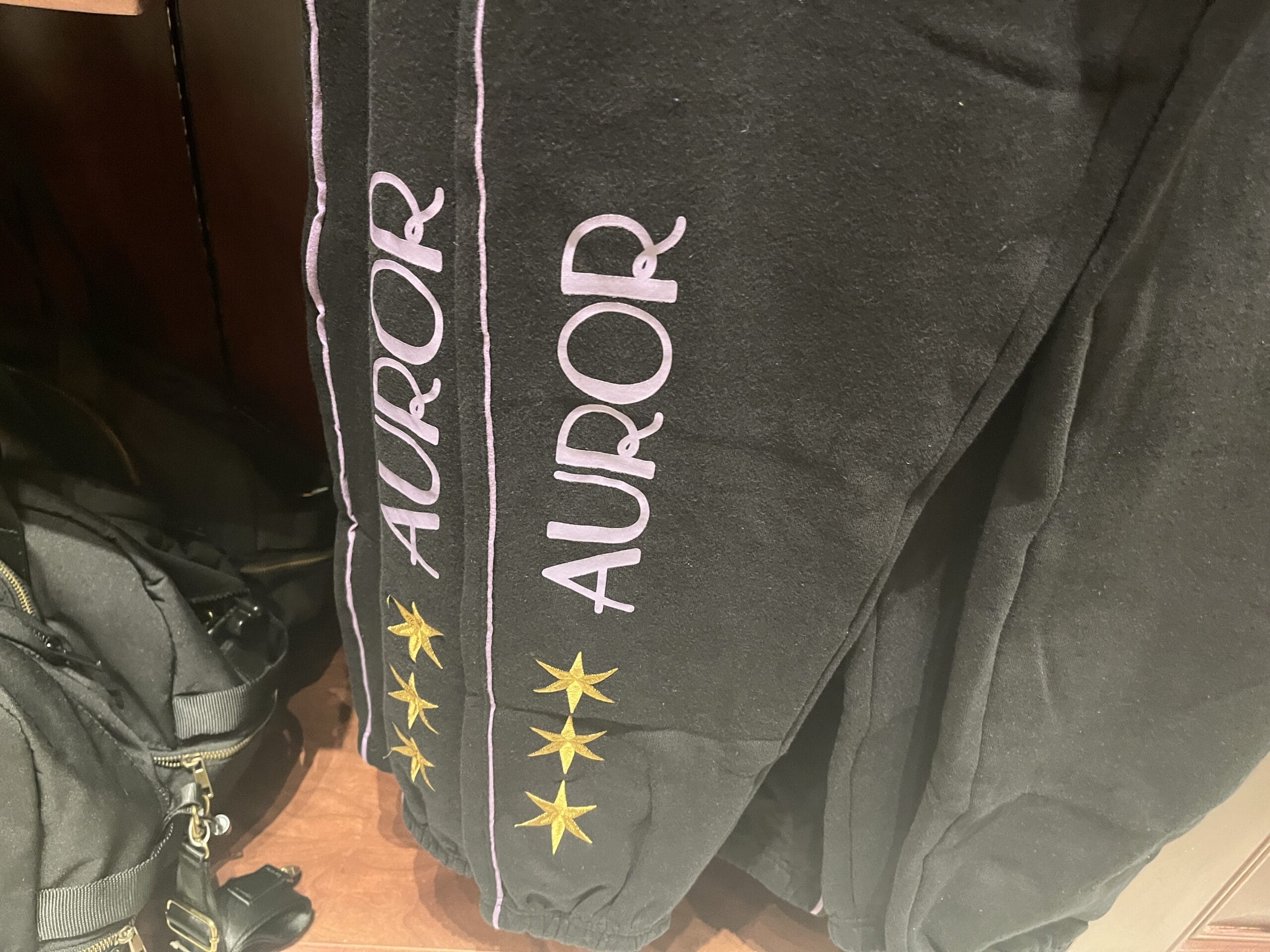 Black pants featuring "AUROR" and three gold stars—perfect for fans of Wizarding World of Harry Potter merchandise.