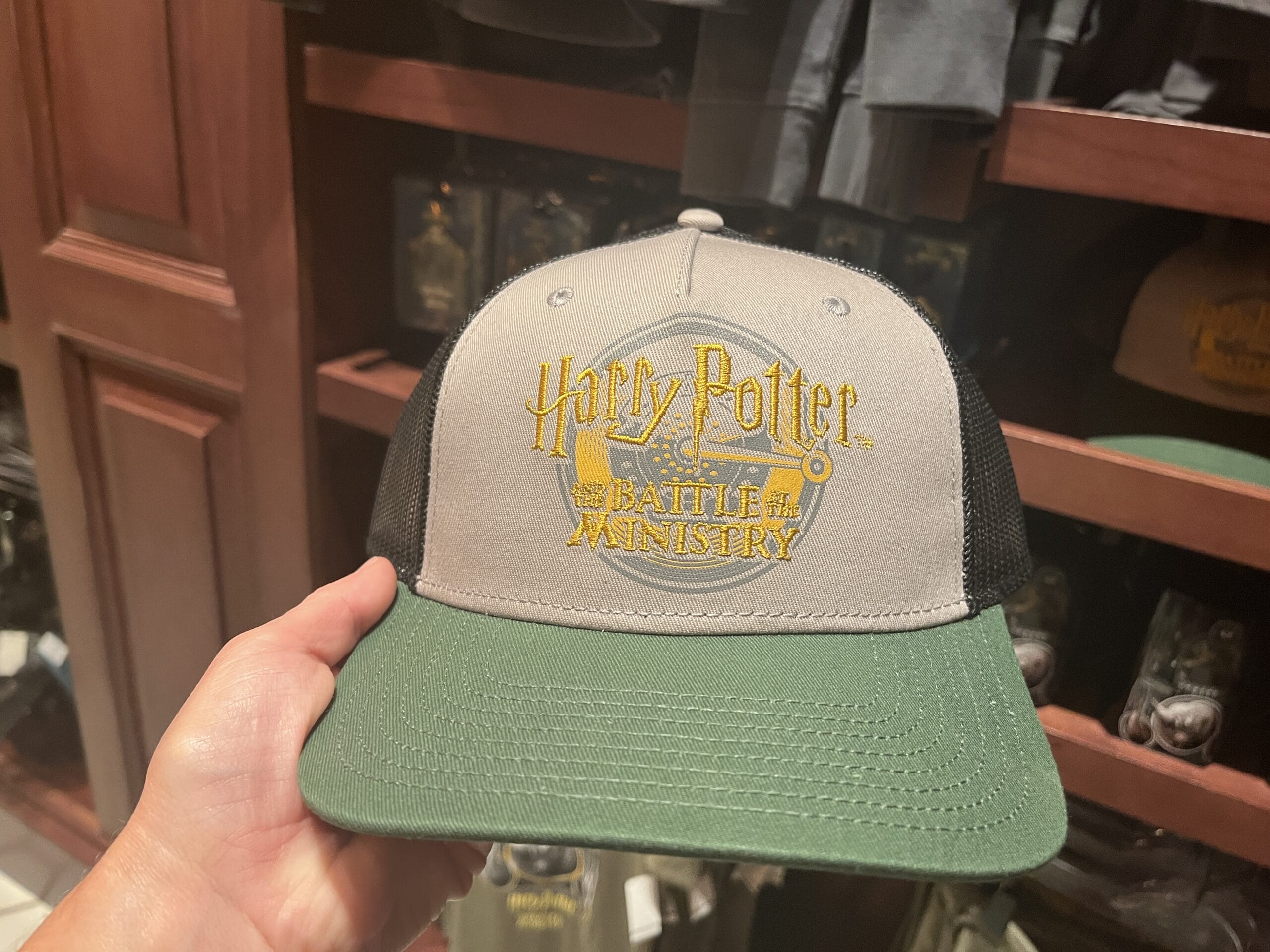A hand holds a "Battle of the Ministry" baseball cap—perfect Wizarding World merchandise for any Harry Potter tour.