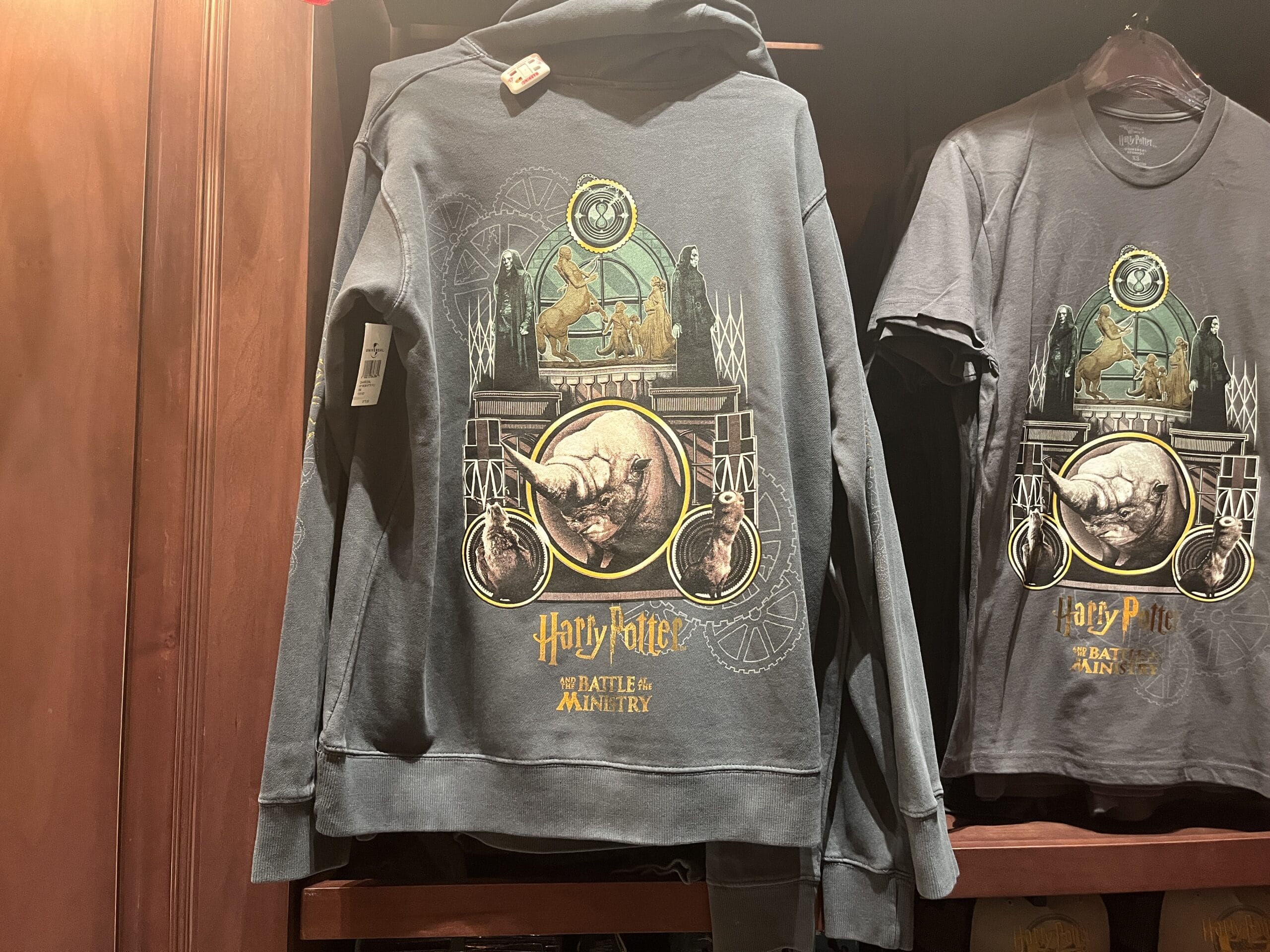 Dark hoodie and t-shirt featuring epic Harry Potter merchandise, magical creatures, and "Battle of the Ministry" text.
