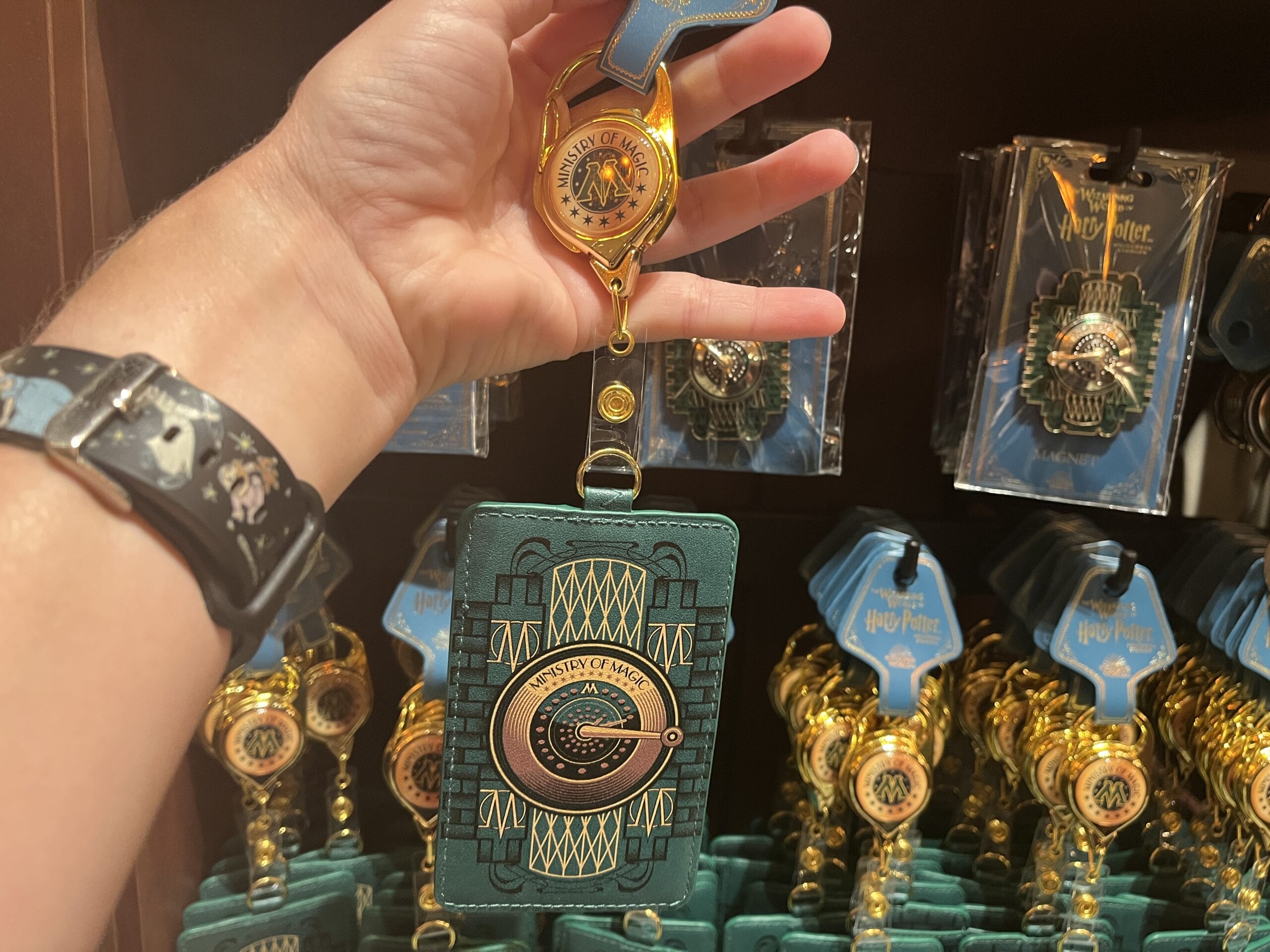 A hand holds a green Hogwarts ID holder with gold detailing—perfect Wizarding World merchandise for any Harry Potter tour.