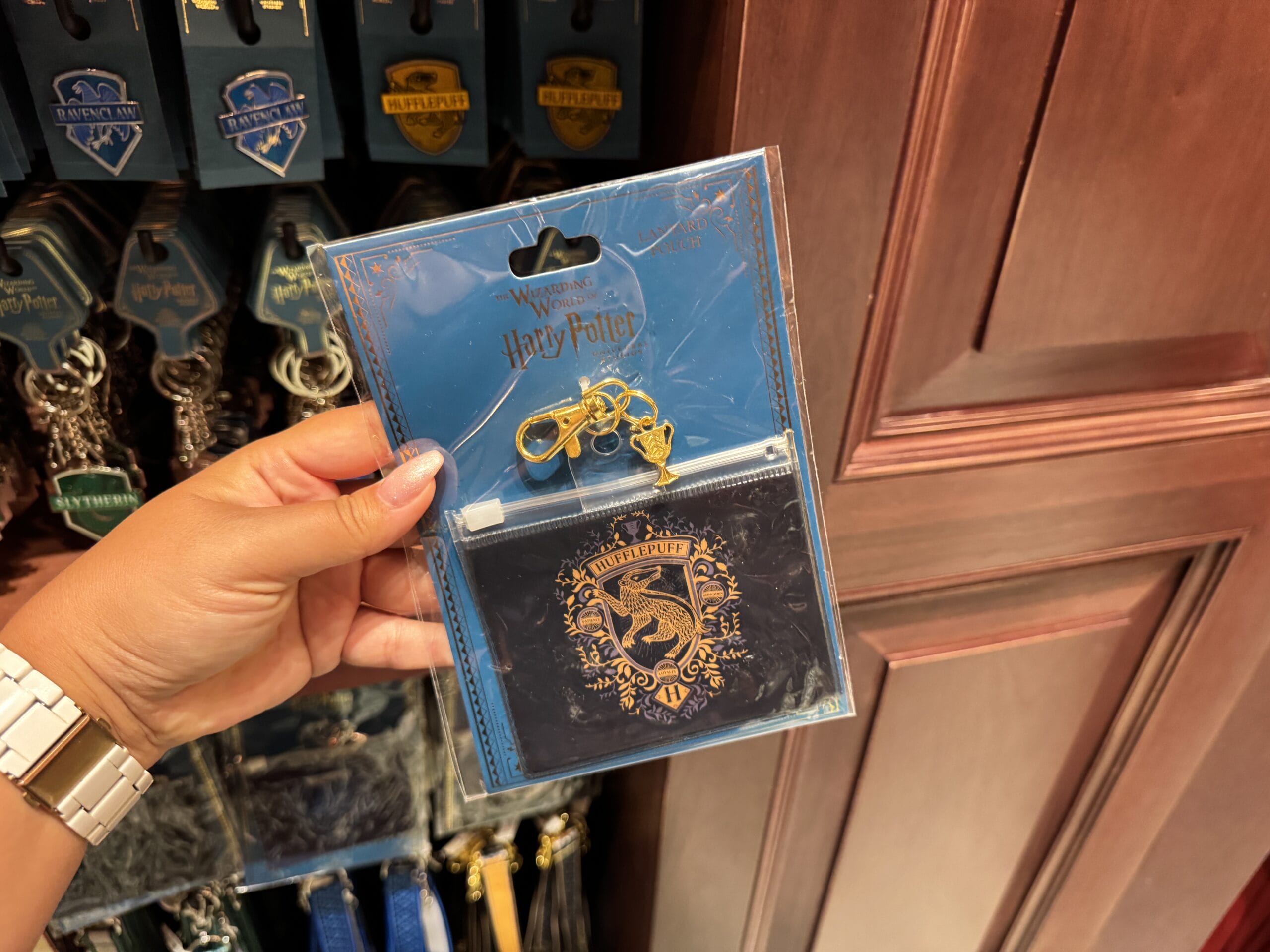 Hand holding a Ravenclaw card holder from Epic Universe, Harry Potter merchandise with a blue lanyard and gold keychain.