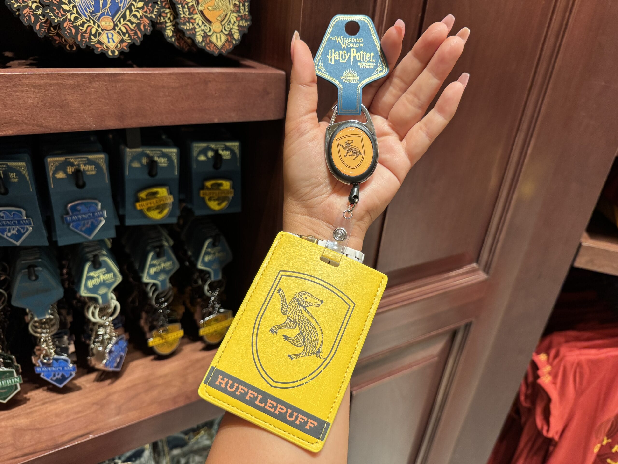 A hand holds a yellow Hufflepuff card holder from the Wizarding World of Harry Potter merchandise store.
