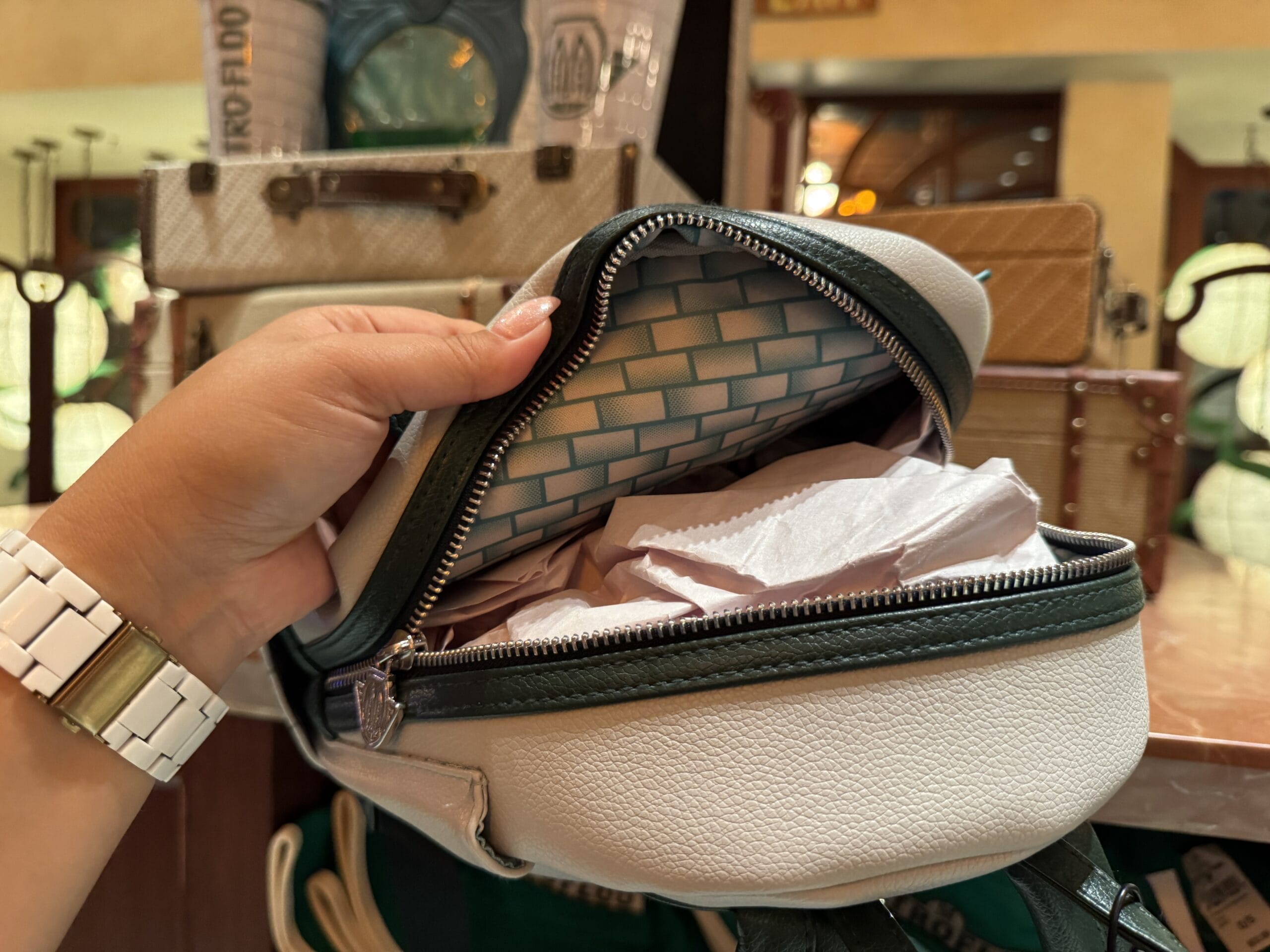A hand holds open a small white purse with blue patterned lining, perfect for carrying Harry Potter merchandise.