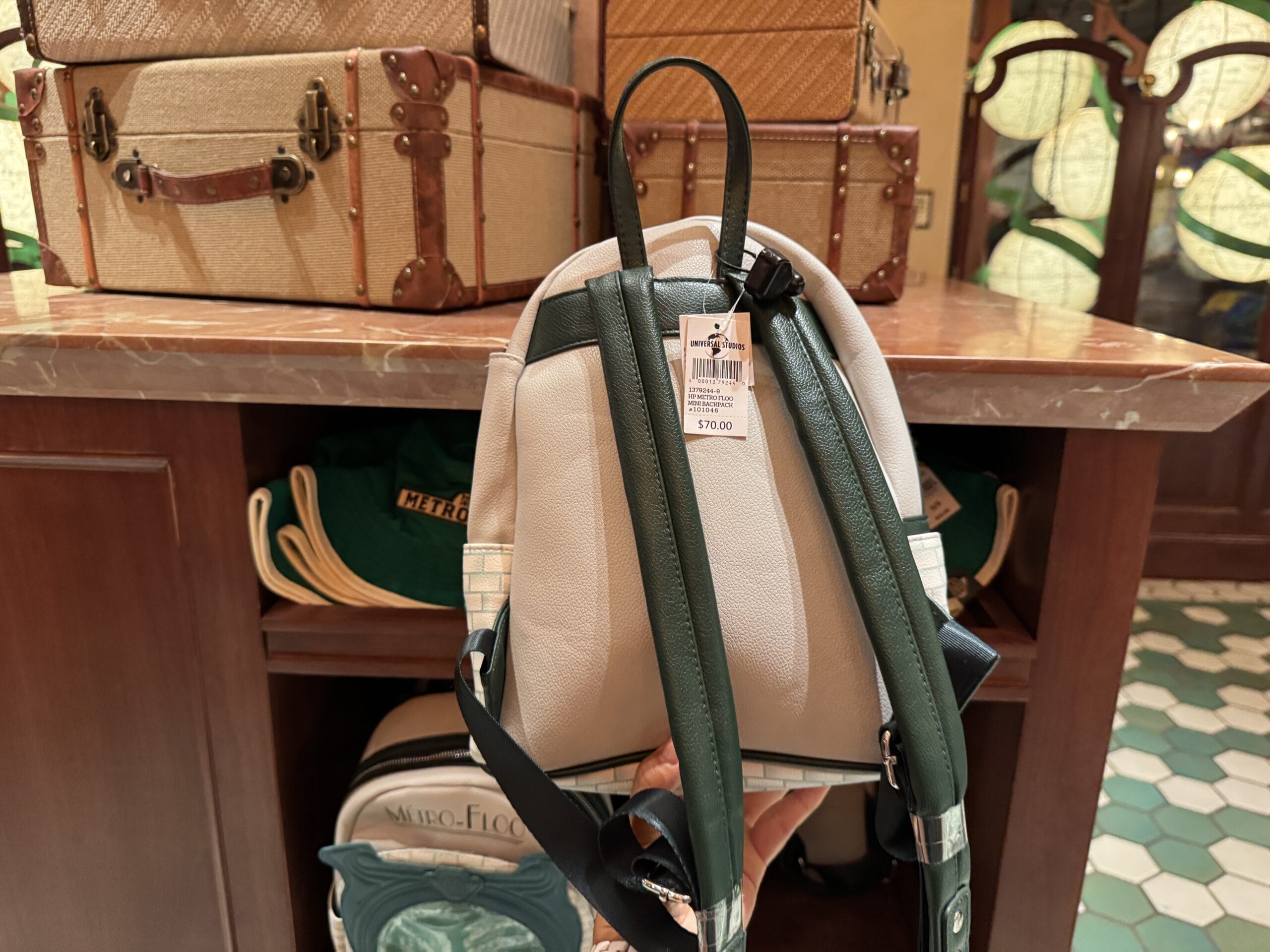 A hand holds a small white and green backpack with a $79 tag, perfect Harry Potter merchandise for Wizarding World fans.
