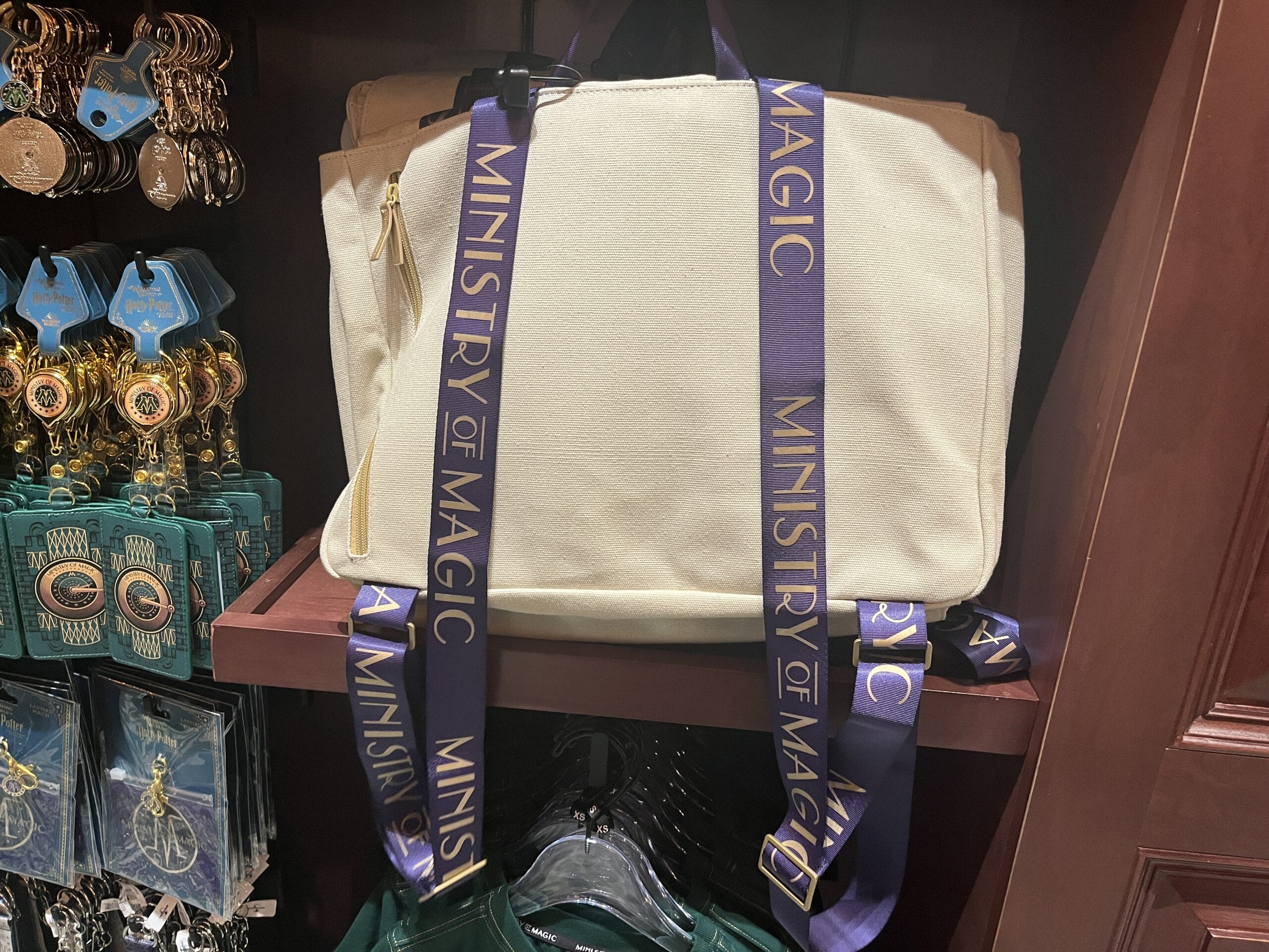 Cream-colored bag with purple "Ministry of Magic" straps, a must-have Epic Universe Wizarding World of Harry Potter merchandise.