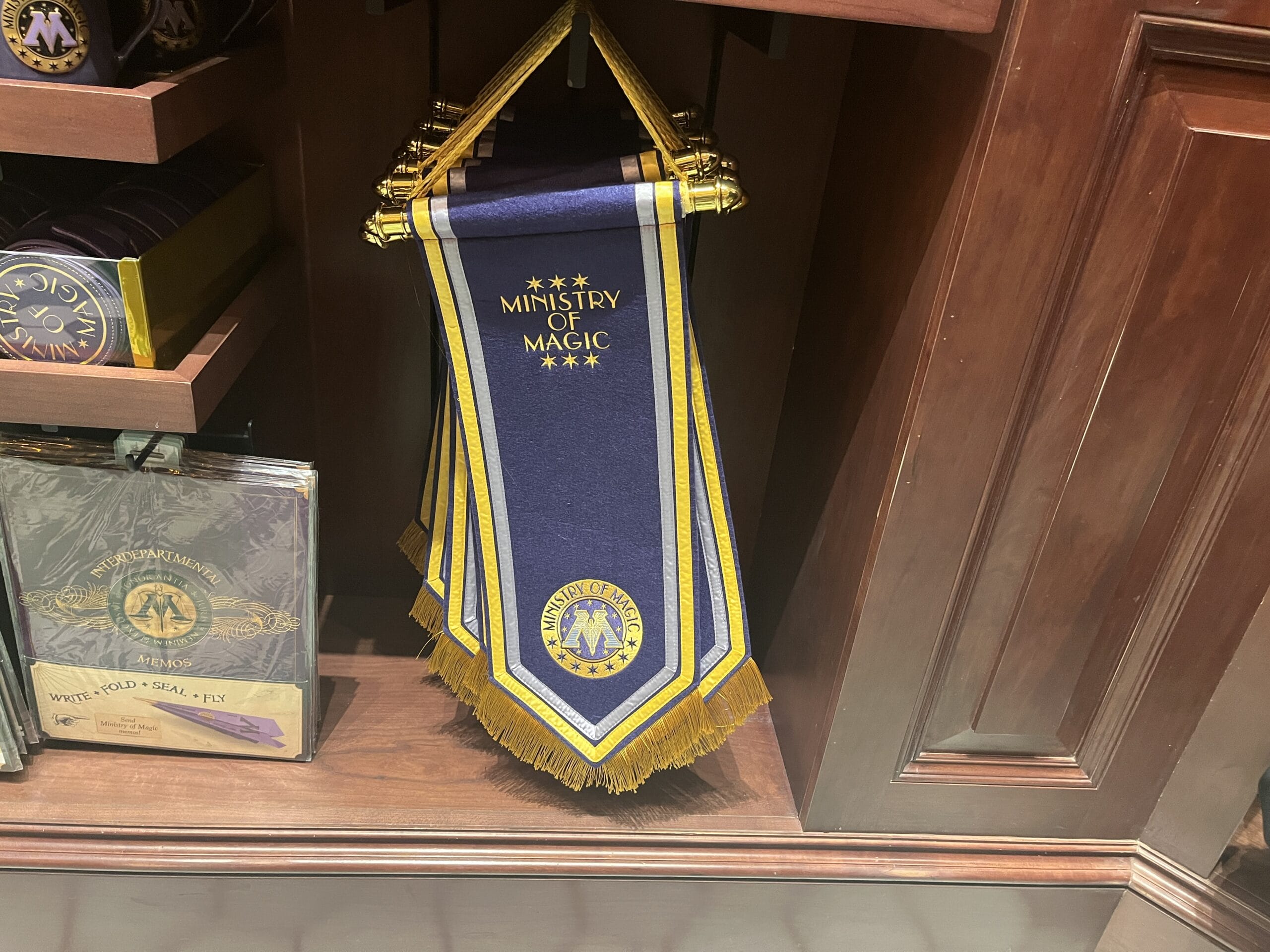 A blue and gold "Ministry of Magic" banner joins Wizarding World of Harry Potter merchandise on the store shelf.