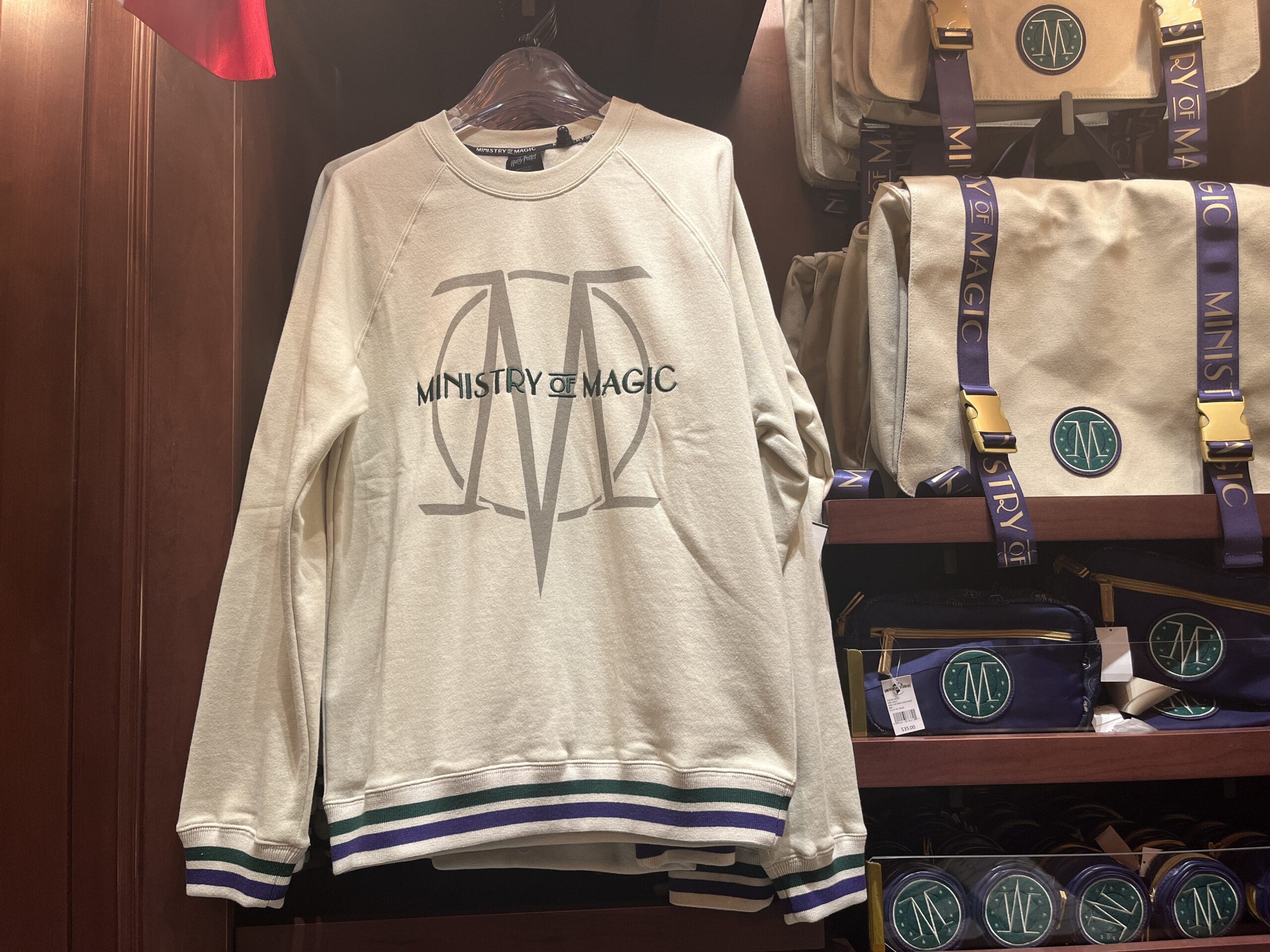 Cream sweatshirt with "Ministry of Magic" logo, perfect Wizarding World of Harry Potter merchandise for fans.