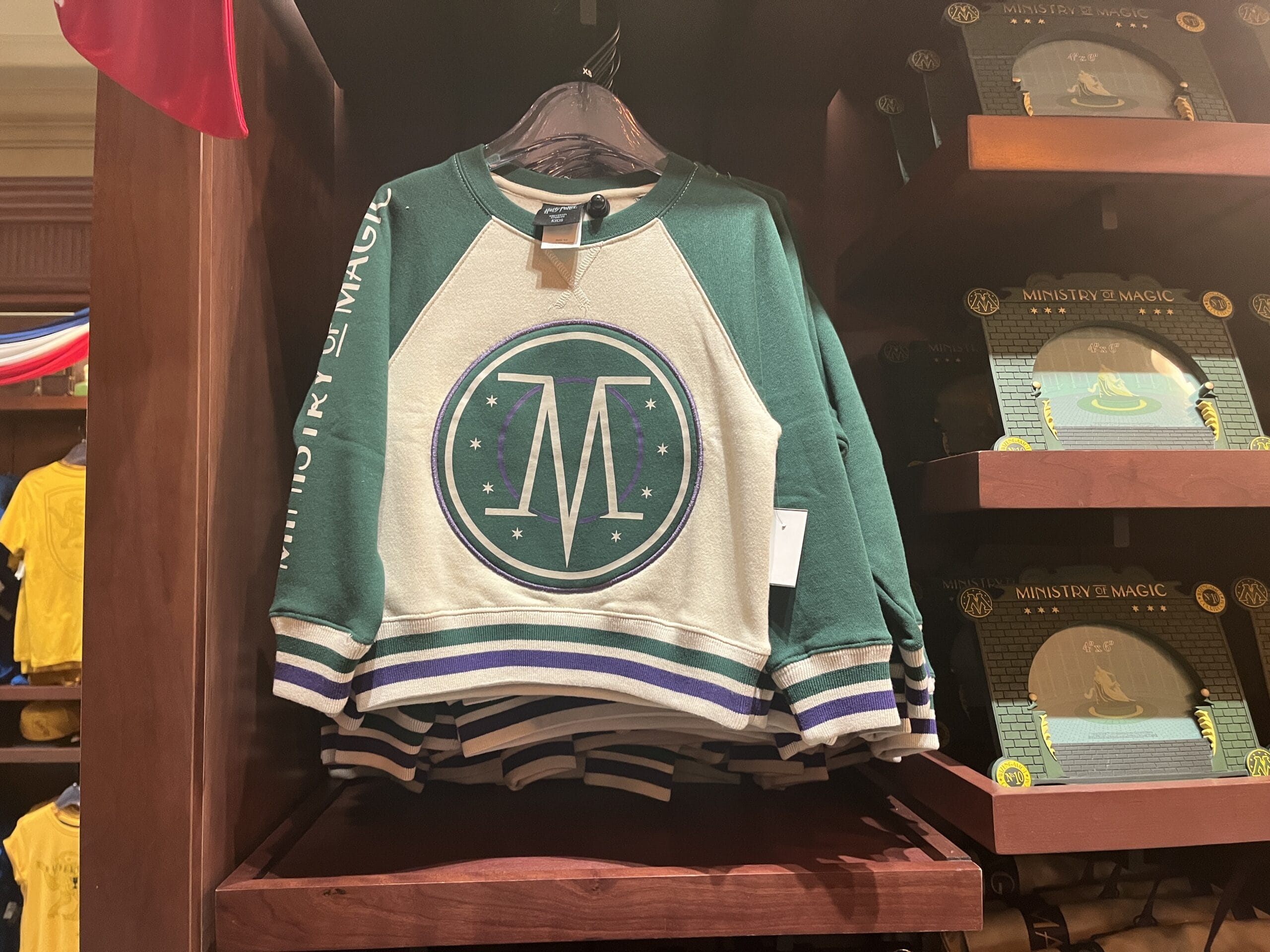 A green and white sweatshirt with the Ministry of Magic logo is featured among Wizarding World of Harry Potter merchandise.