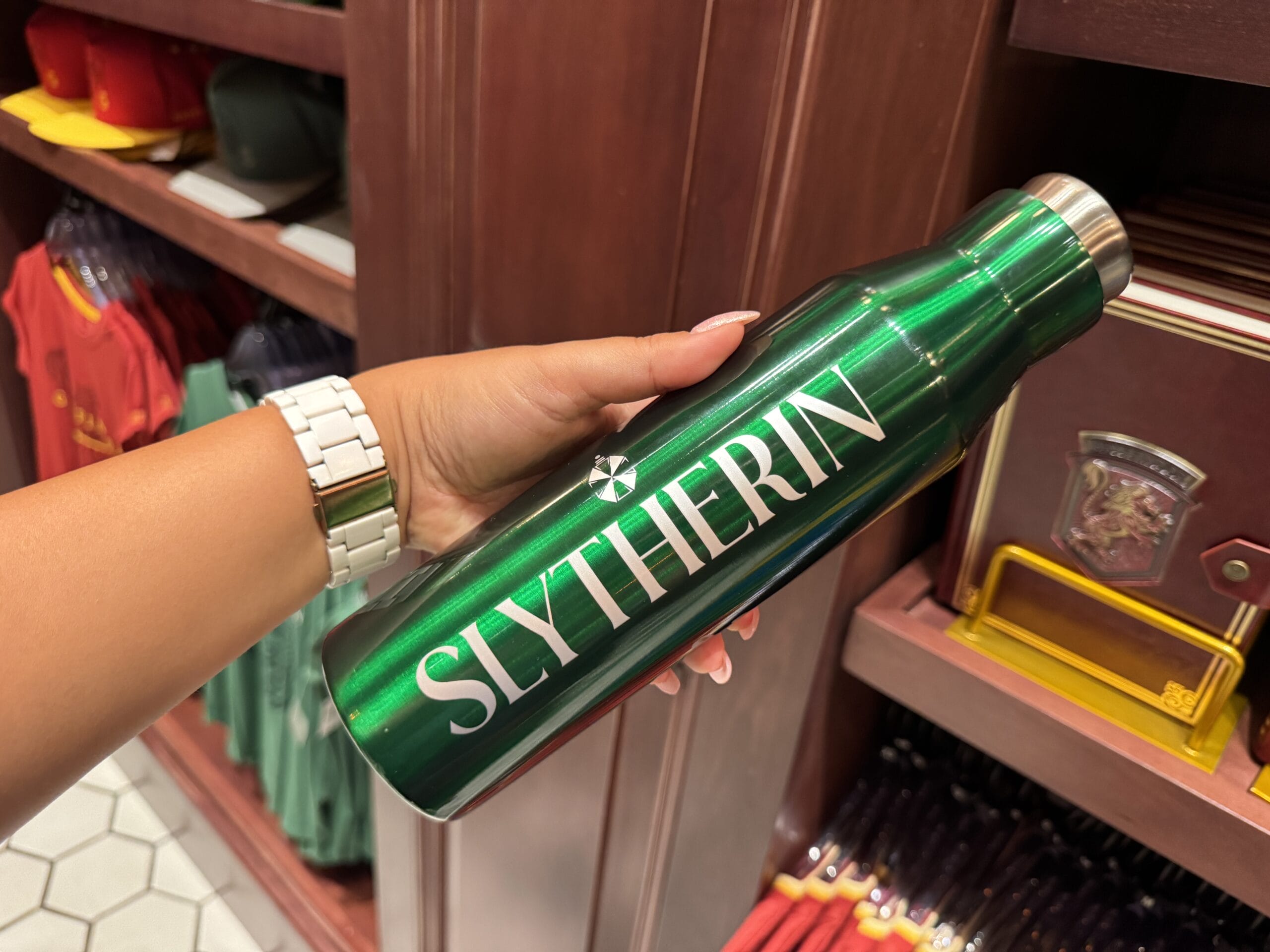 A hand holds a shiny green SLYTHERIN bottle—Wizarding World of Harry Potter merchandise shines for epic fans.