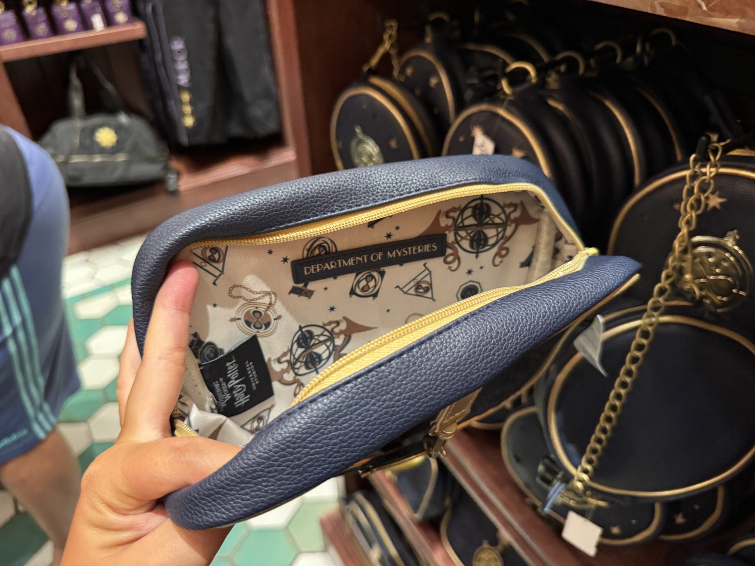 A hand holds open a blue purse with "Department of Mysteries"—a unique piece of Wizarding World Harry Potter merchandise.