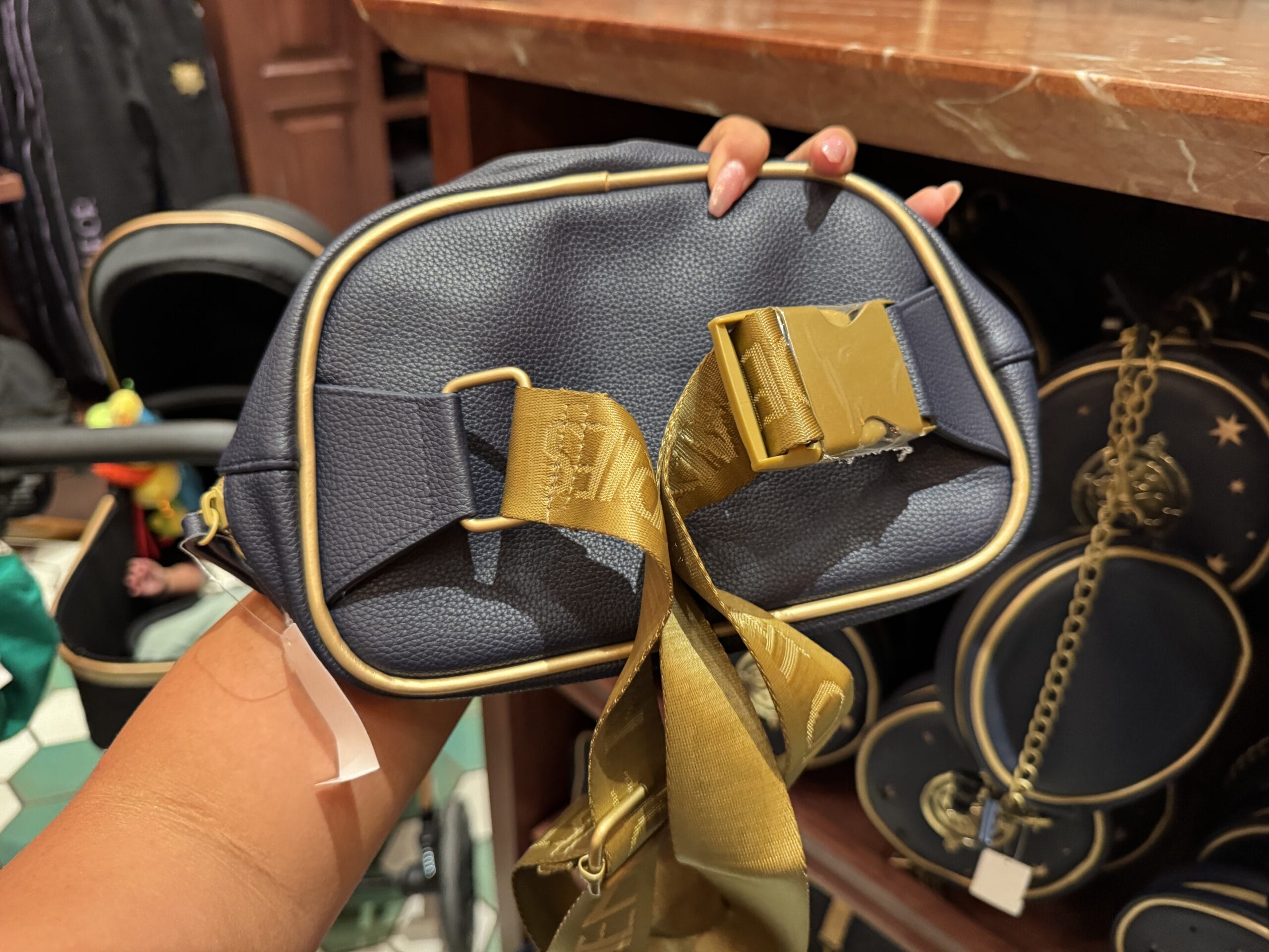A hand holds a small navy blue bag with gold trim—perfect Wizarding World merchandise for your Harry Potter tour.