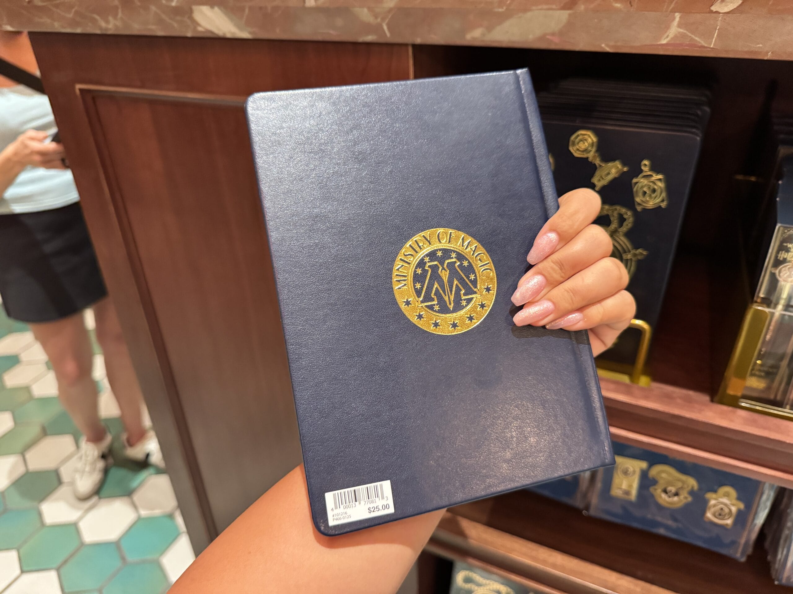 Person holding Wizarding World of Harry Potter merchandise notebook in a store, price tag and shelves visible in background.