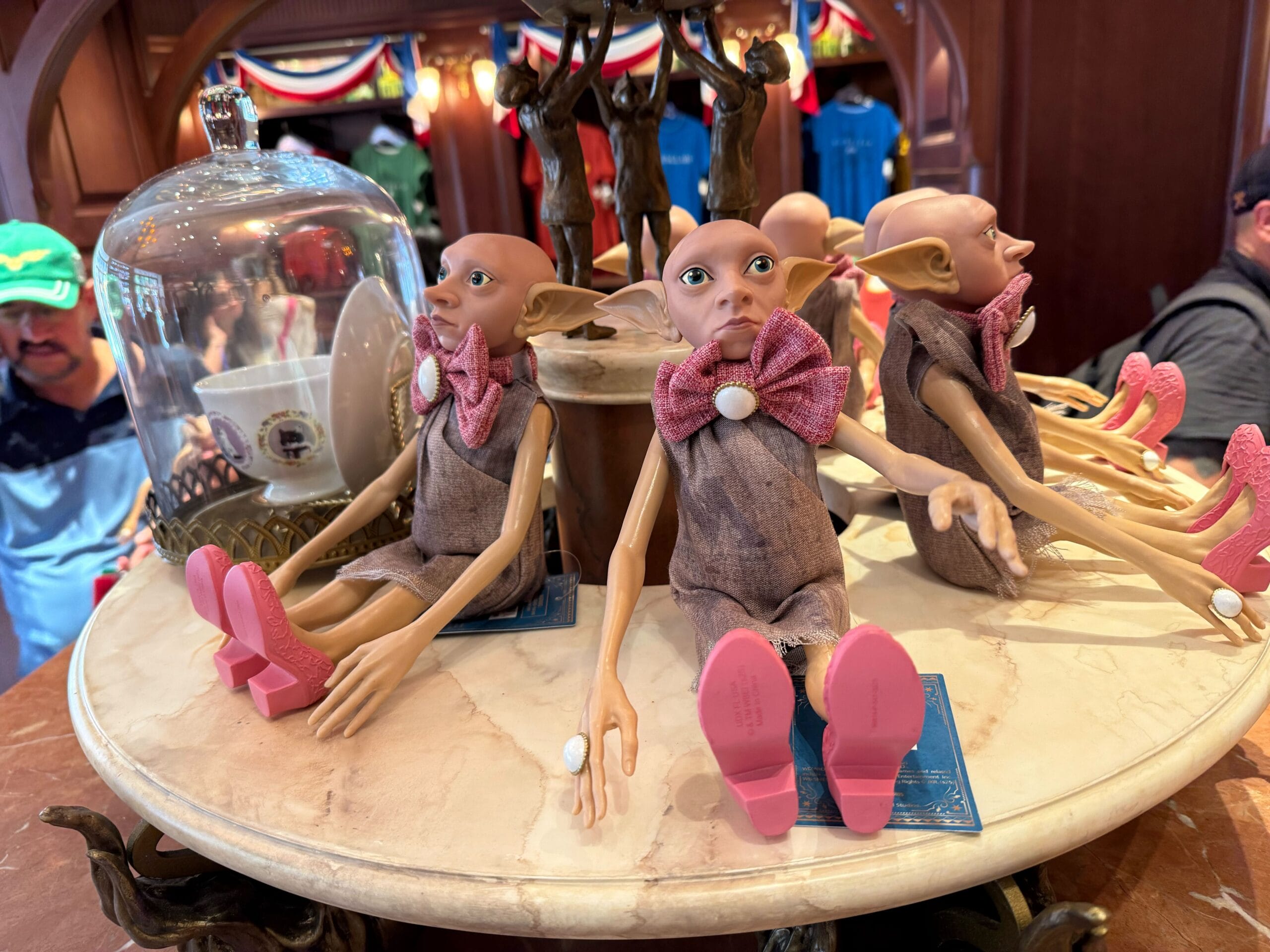 Several elf dolls with large ears and pink shoes sit on a marble display, part of Wizarding World merchandise.