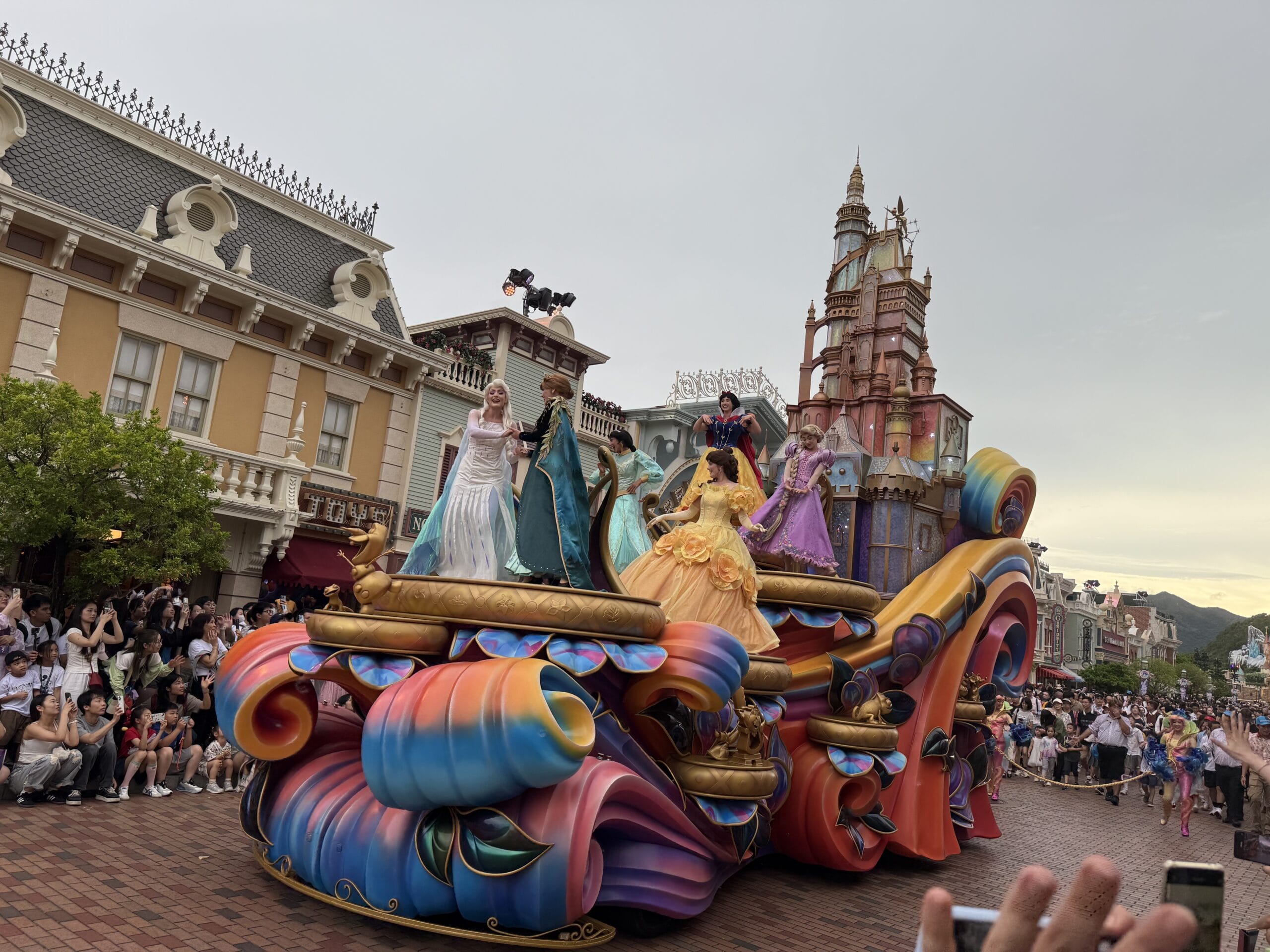 Colorful parade float with five princesses waving during the Friendtastic Parade at Hong Kong Disneyland.