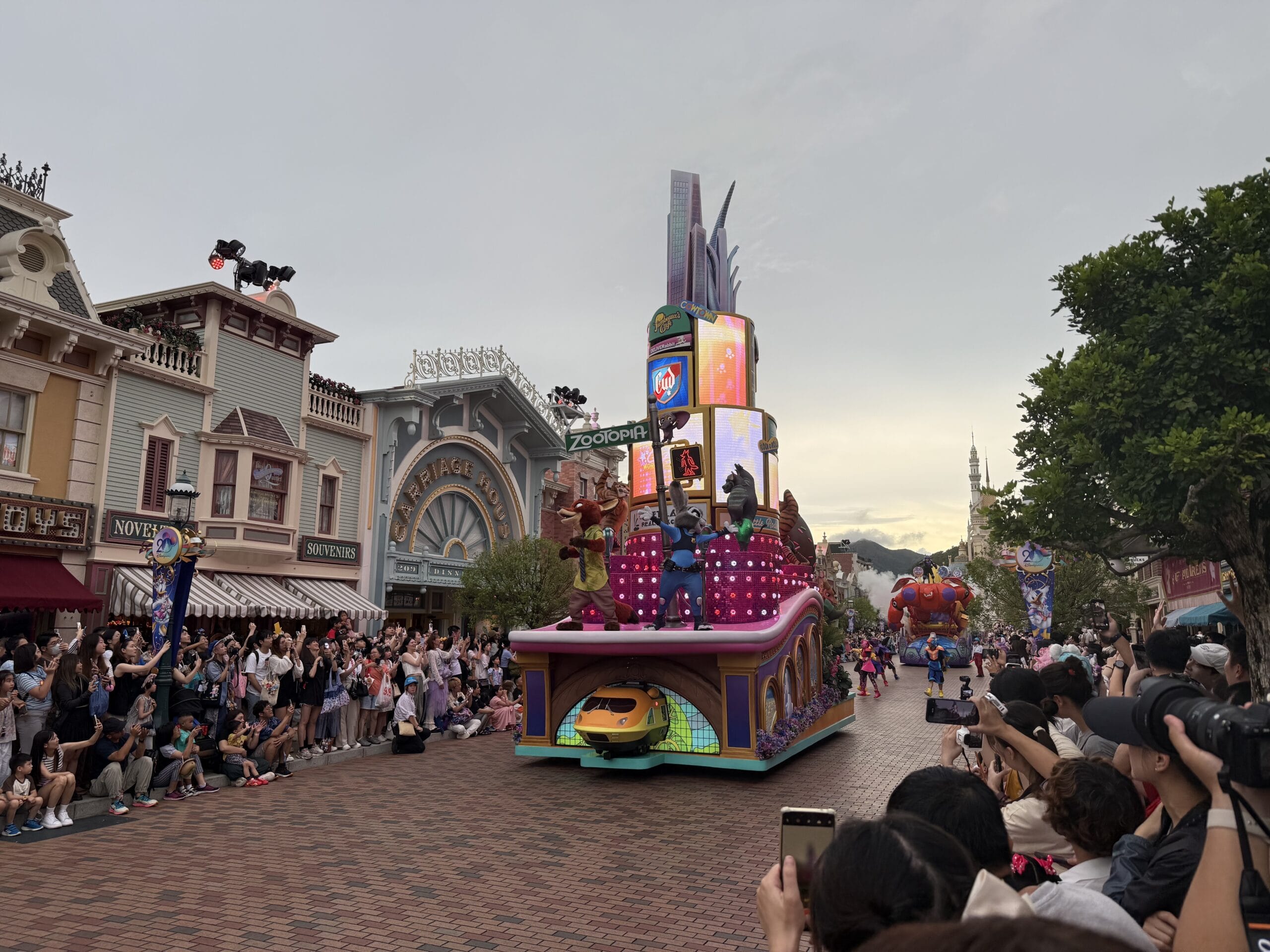 A colorful Friendtastic Parade float moves down a street lined with cheering crowds at Hong Kong Disneyland.