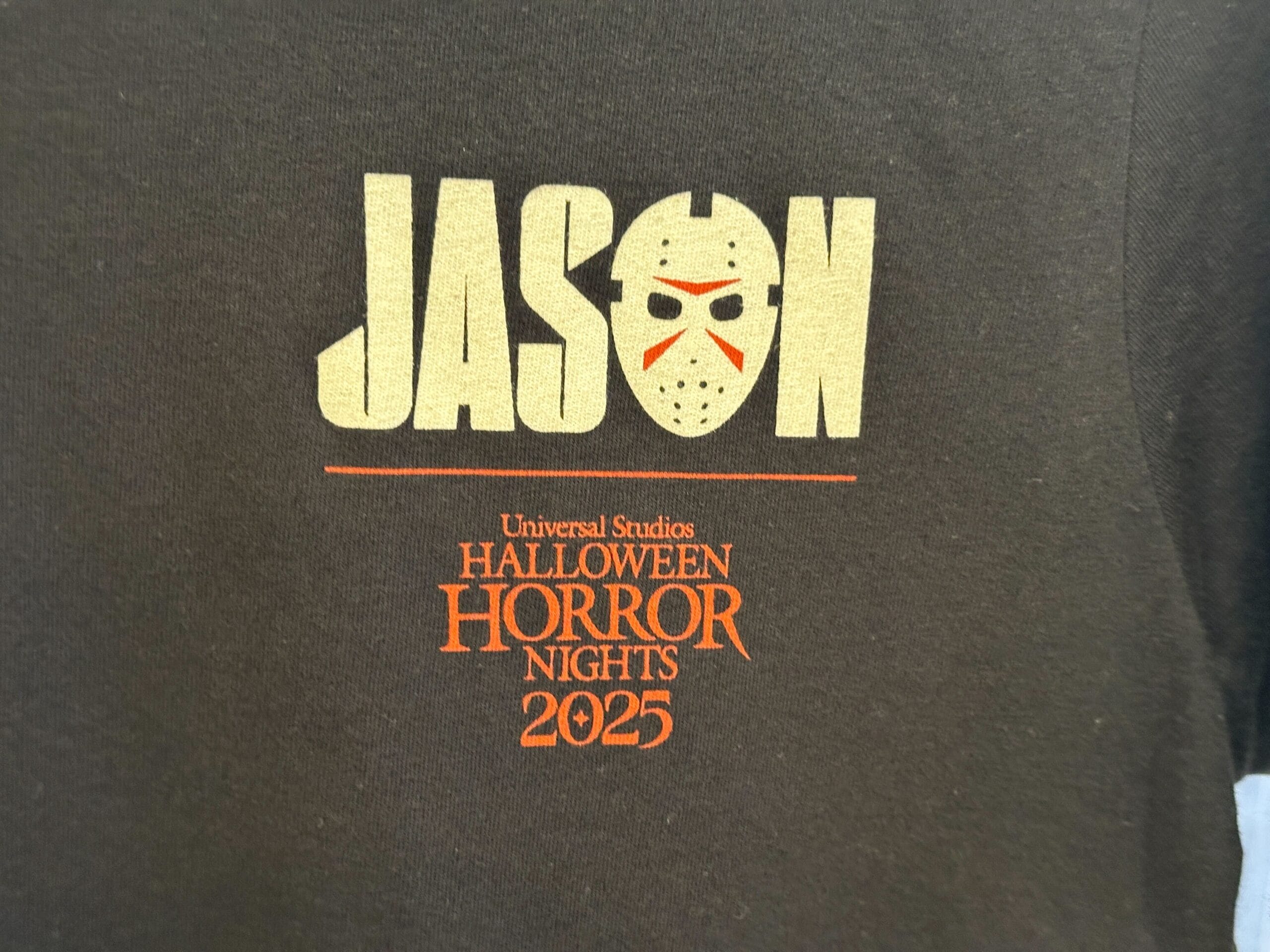 Black T-shirt with "JASON" and a hockey mask, plus "Friday the 13th Halloween Horror Nights 2025" in orange below.