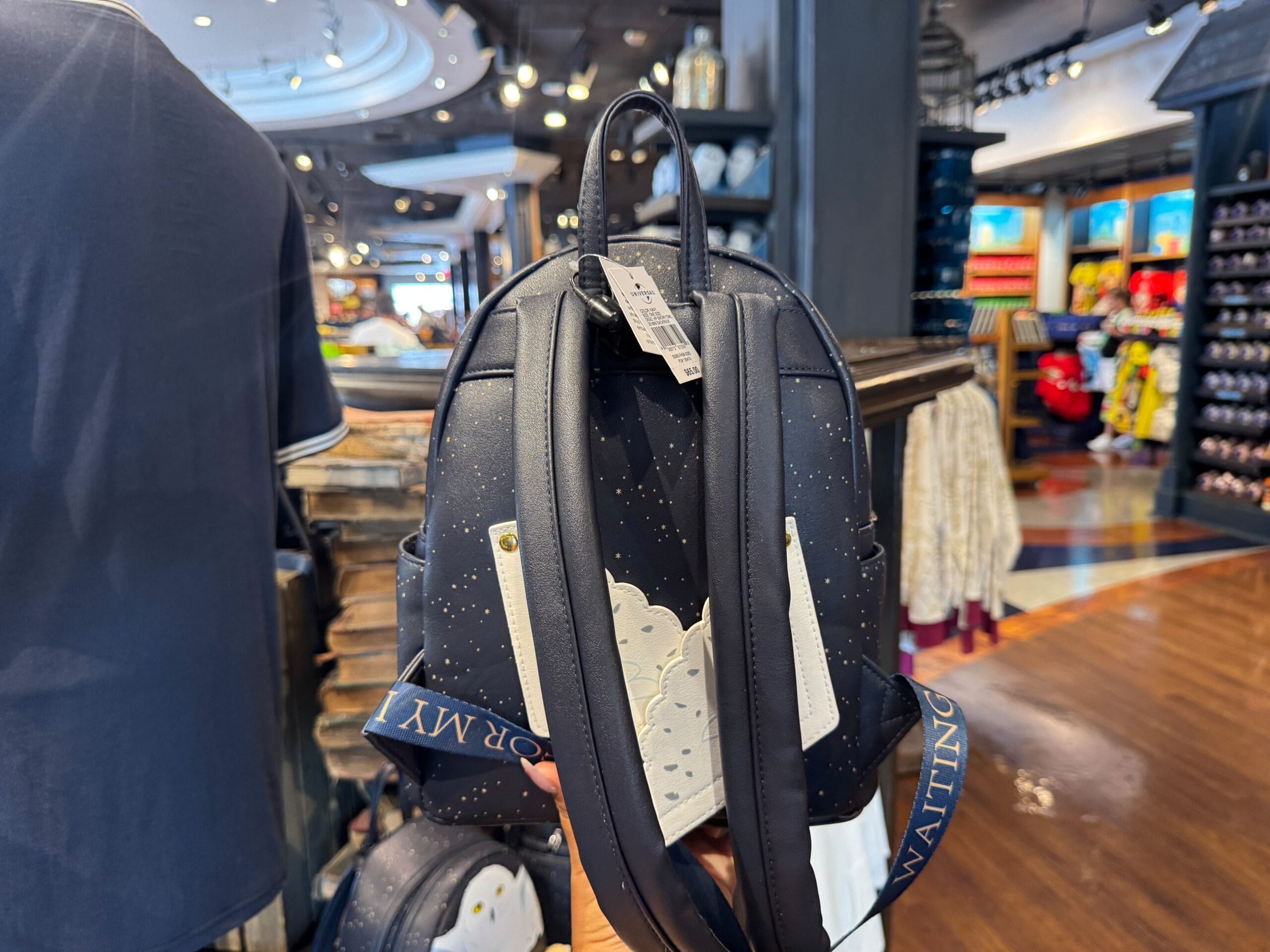 A hand holds a small black backpack with a cloud design, perfect for any Harry Potter fan waiting for their letter.