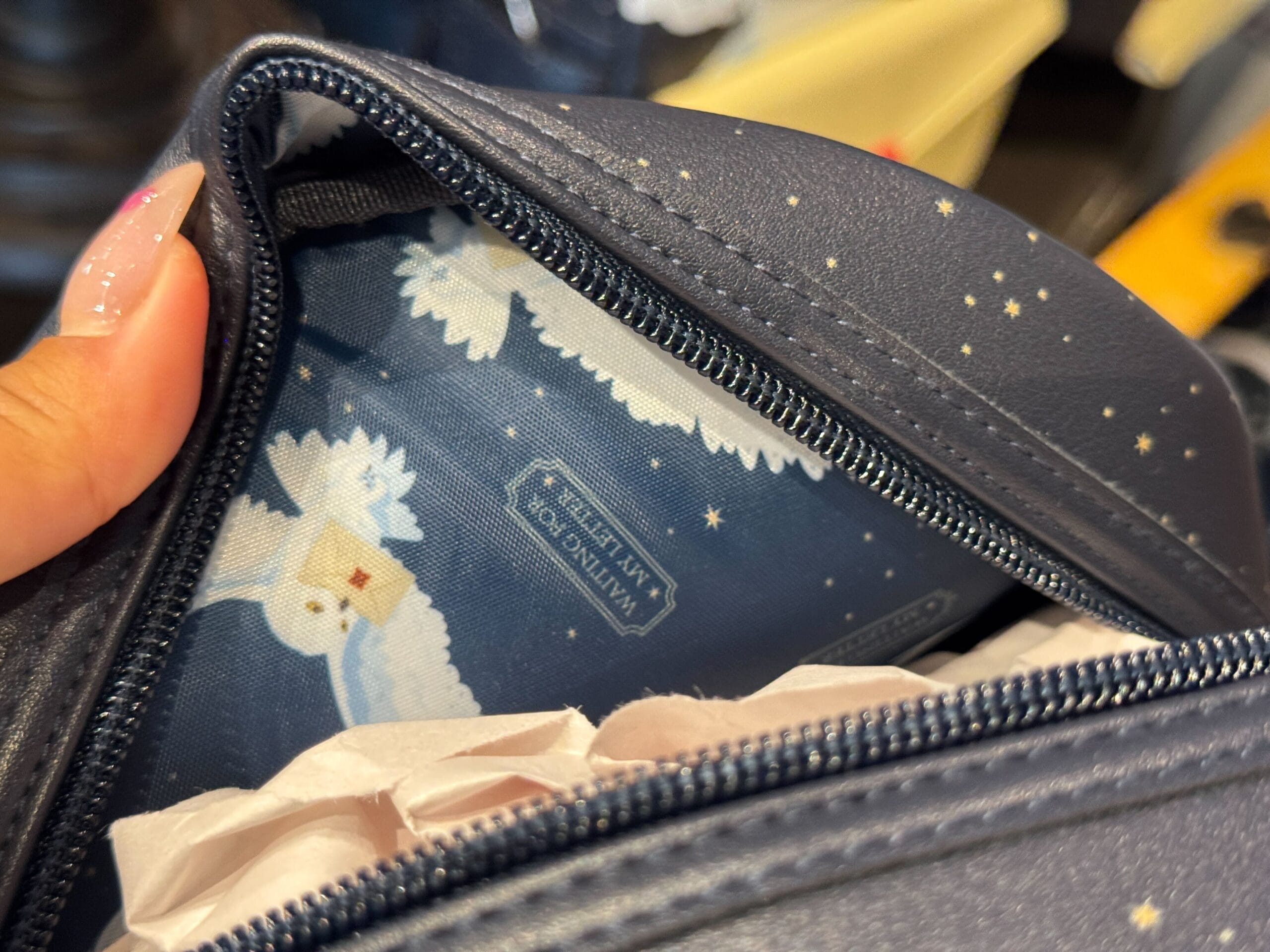 A close-up of a blue zippered bag with stars and an interior lining featuring Hedwig and Hogwarts letters.