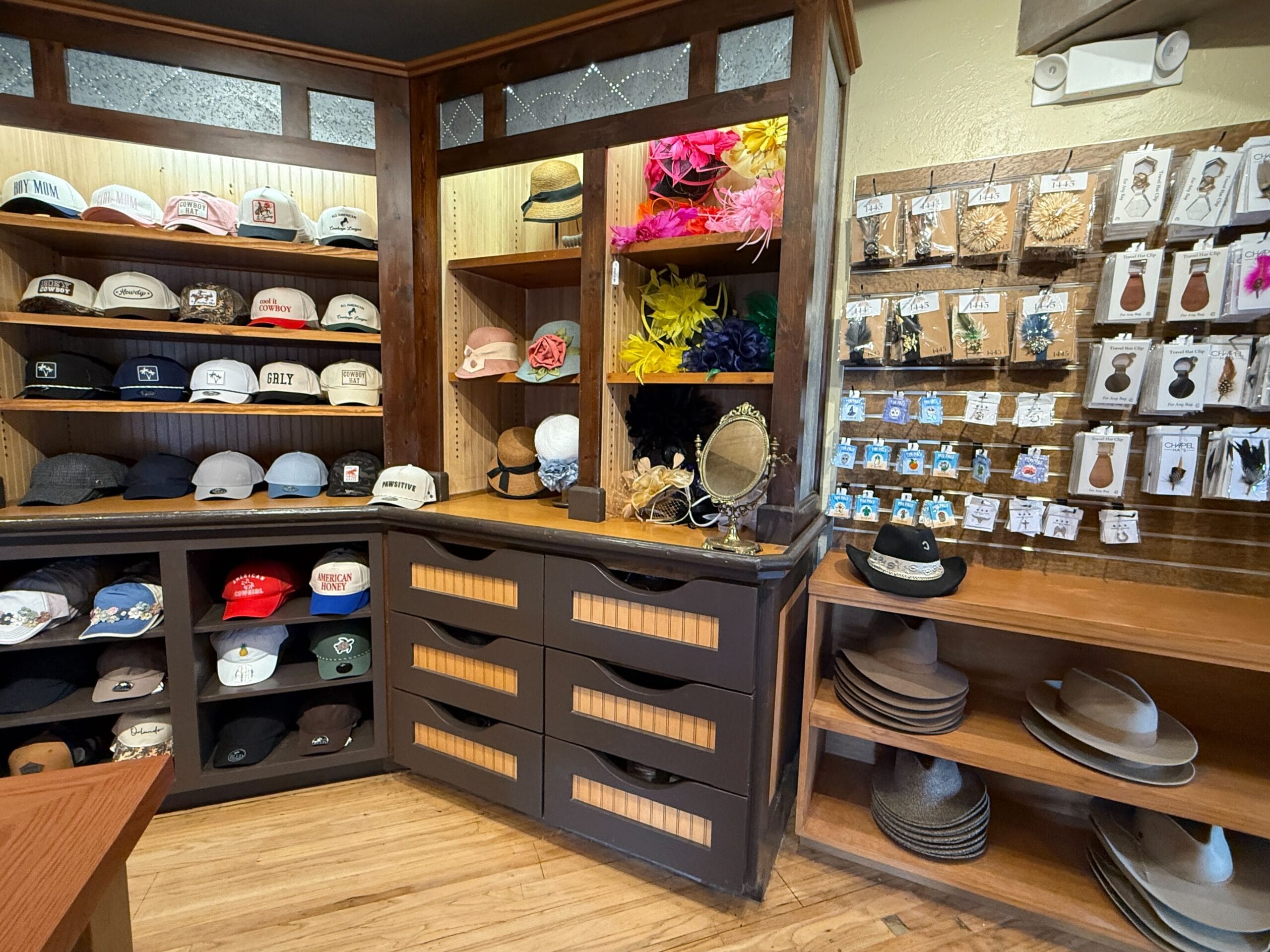 Hat Shop display with hats, caps, headbands, earrings, and accessories on wooden shelves and drawers.