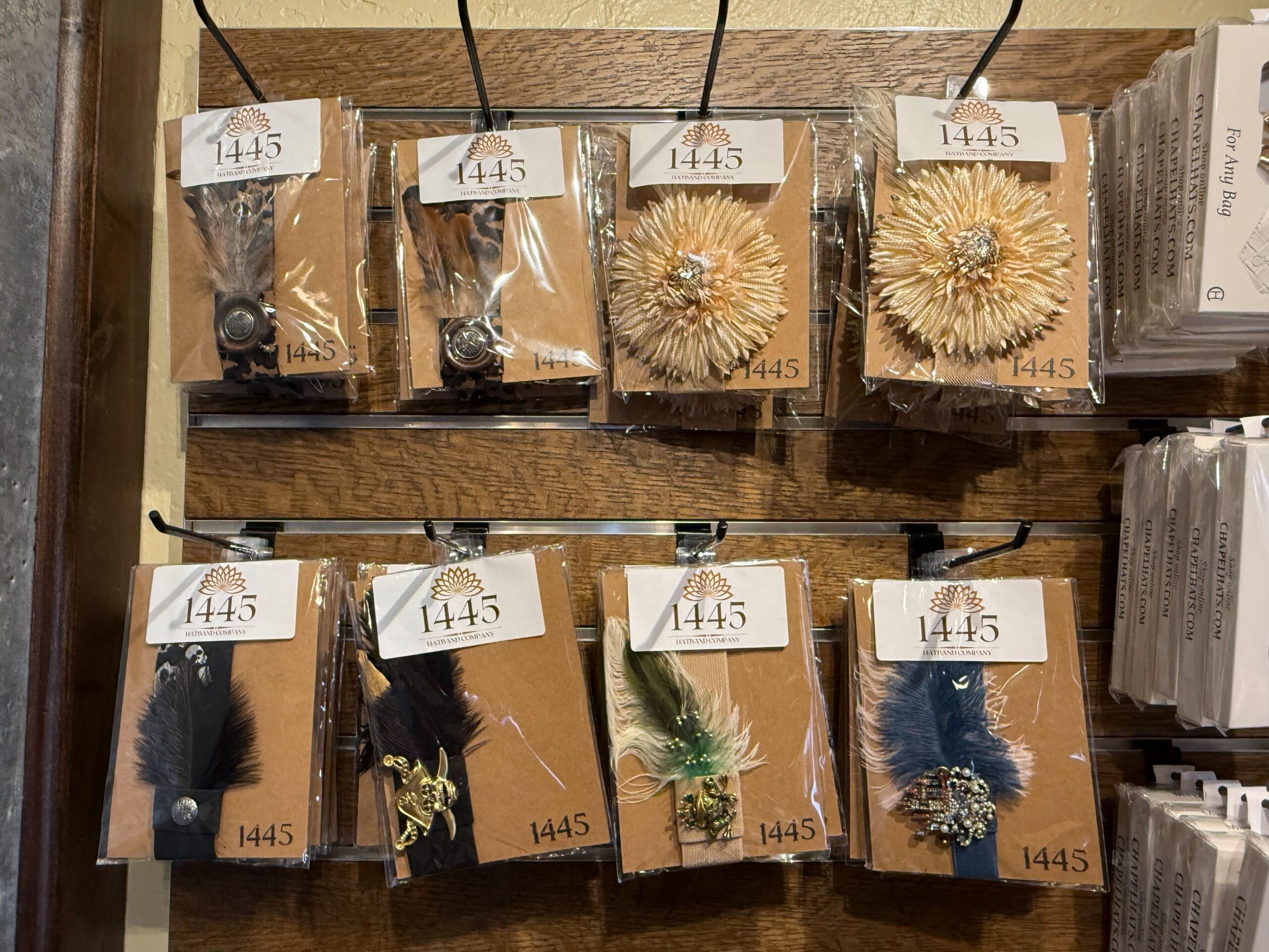 Assorted decorative feather and flower hair clips from the Prairie Outpost displayed on hooks, each on a brown card labeled "1445.