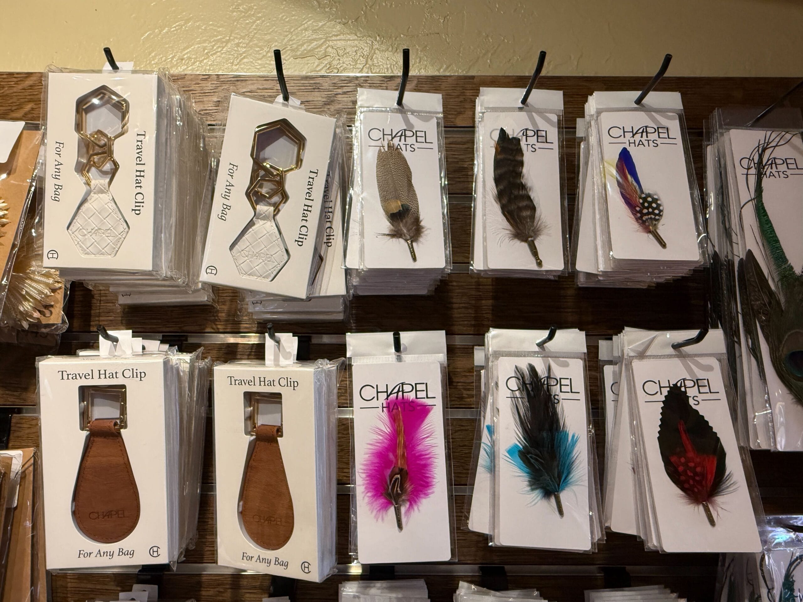 Charming Hat Shop finds: travel hat clips and colorful feather accessories hang in the Prairie Outpost’s rustic display.