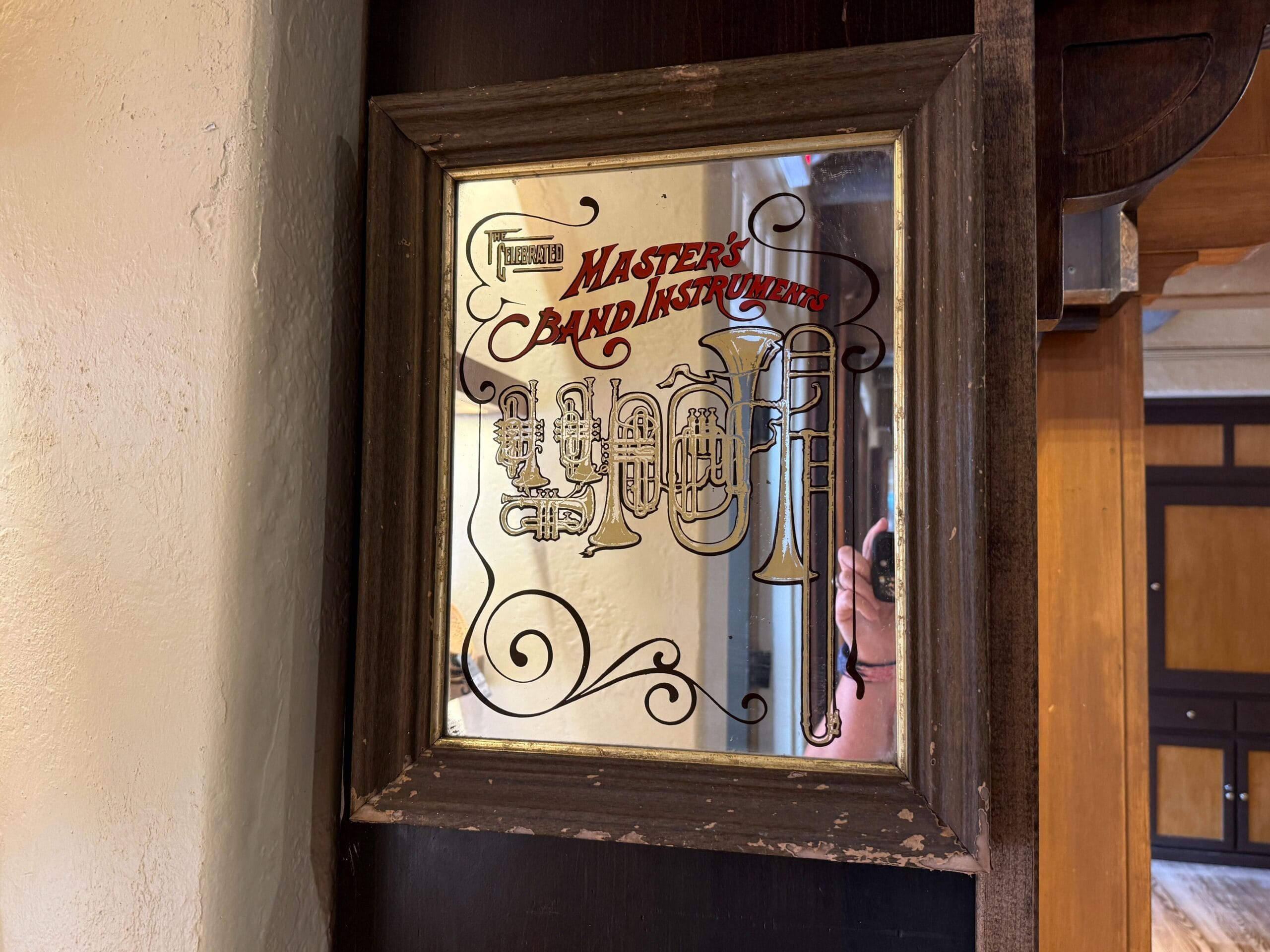 A framed vintage mirror from the Hat Shop with "Master’s Band Instruments" and brass etchings on the glass.