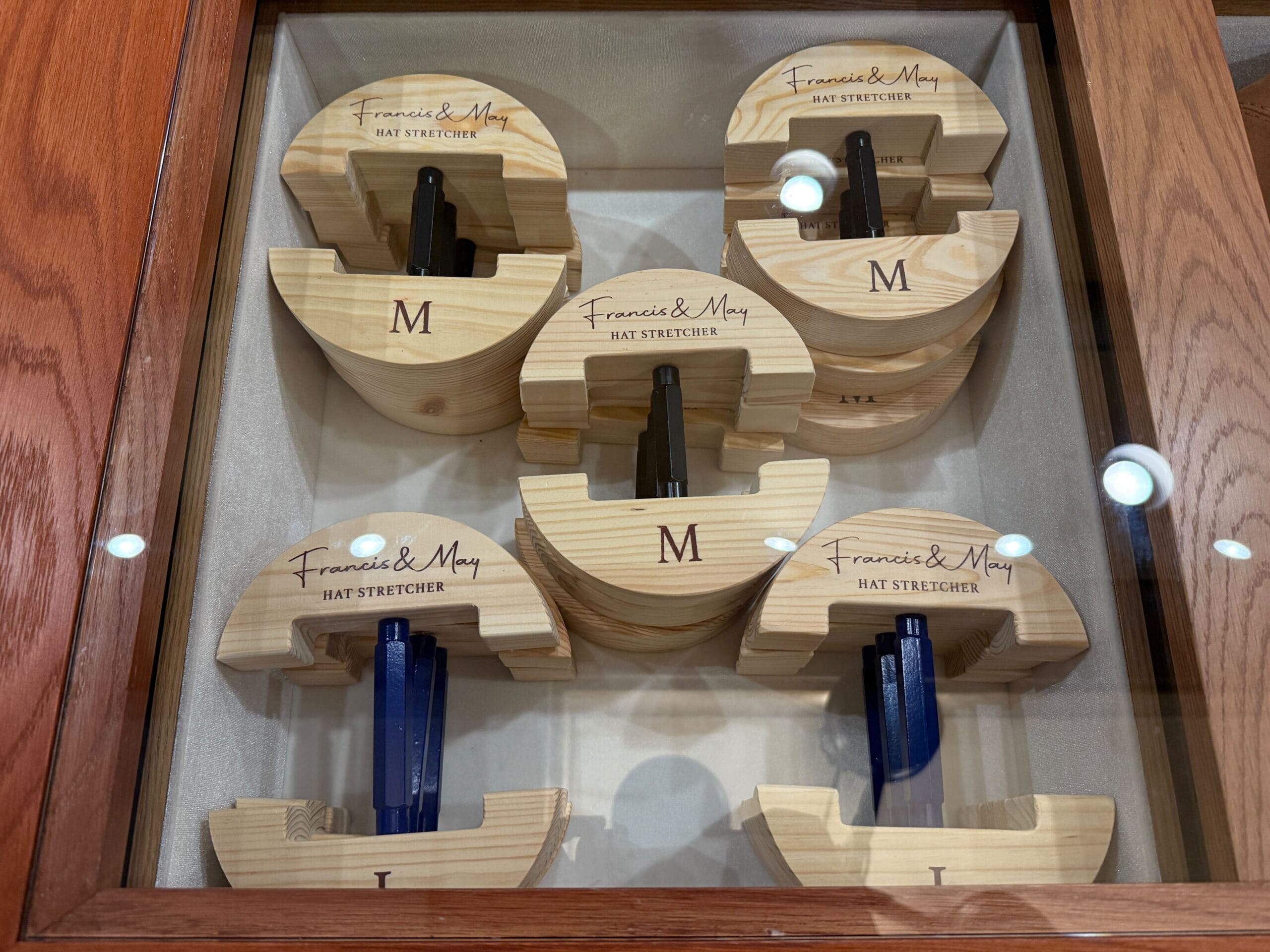 Wooden hat stretchers from the Prairie Outpost hat shop are displayed in a glass case at Magic Kingdom.