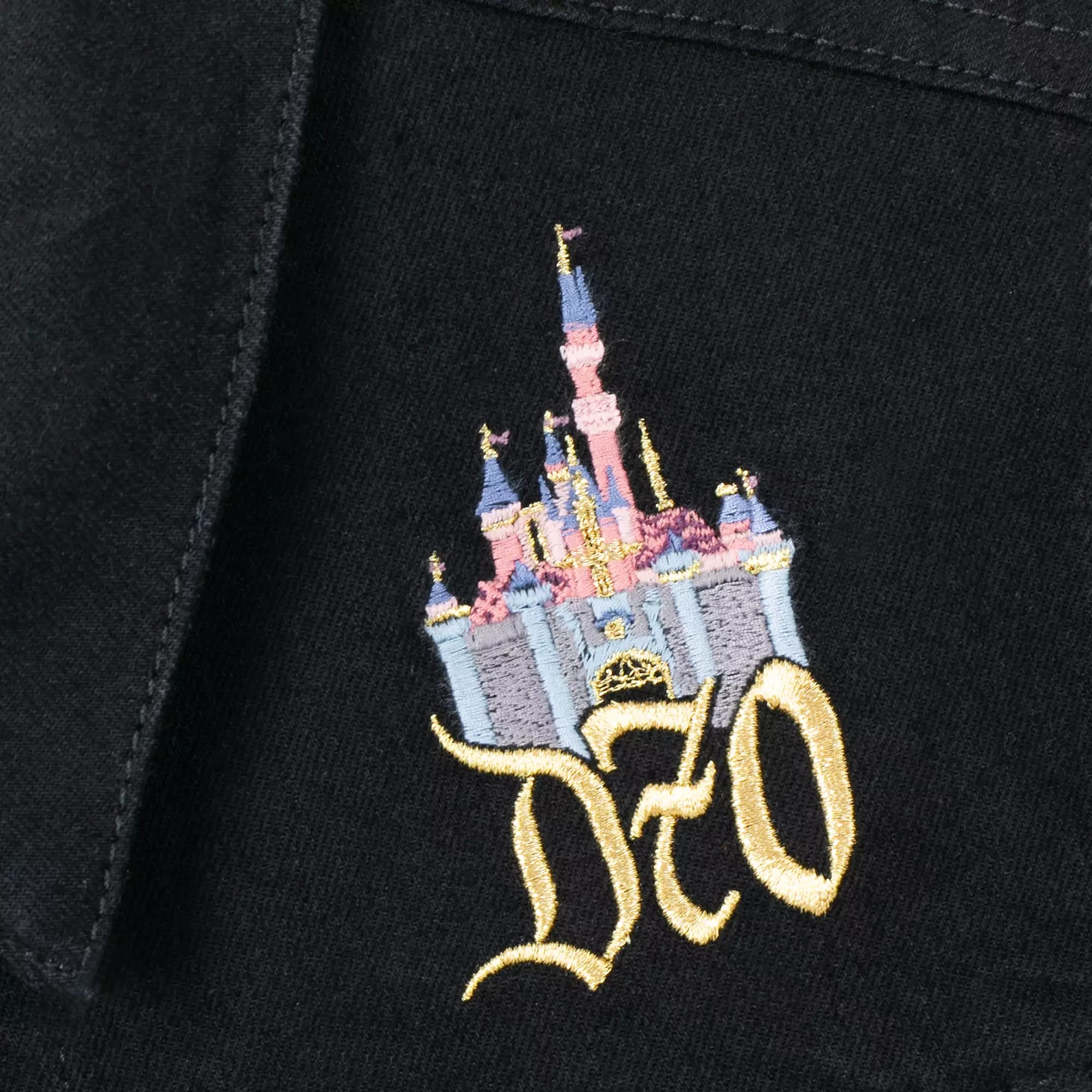 Embroidered pastel castle and gold "D70" on black fabric, celebrating Disney’s 70th anniversary.