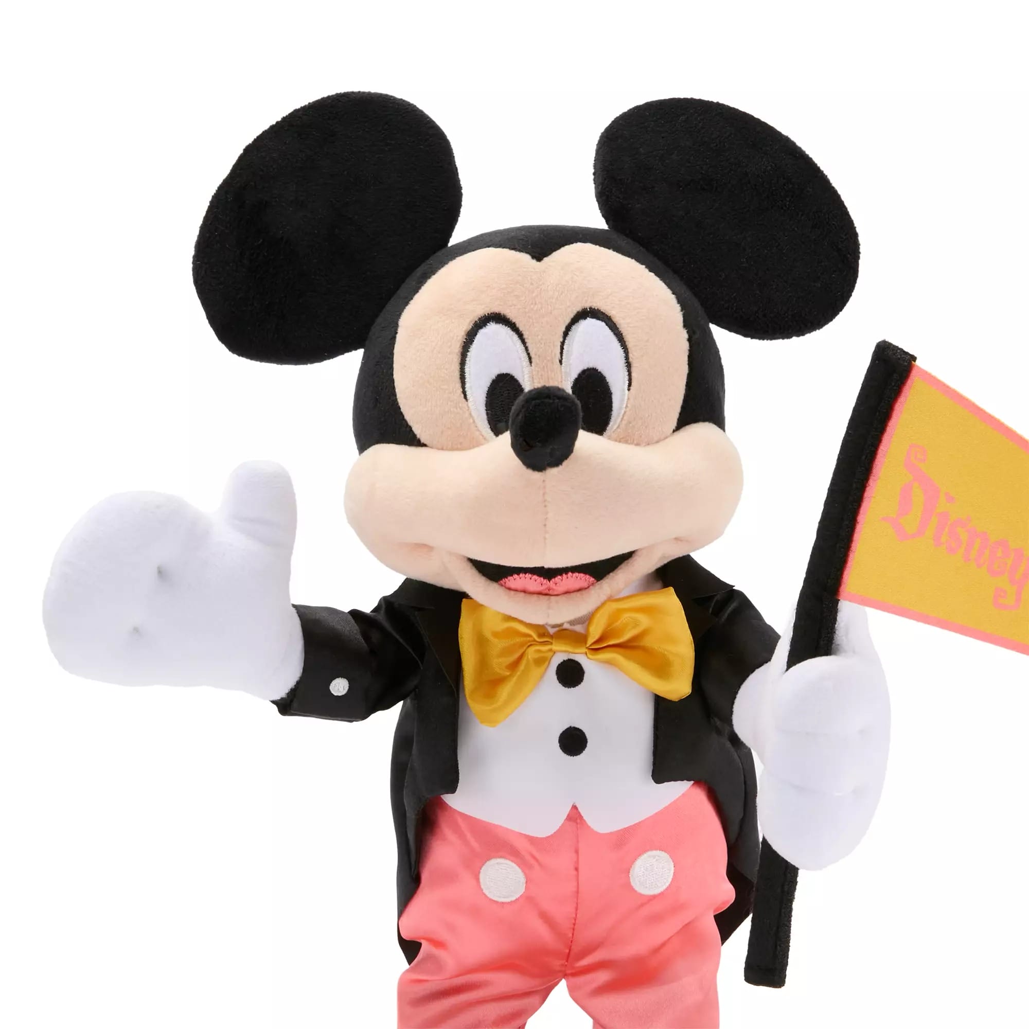 Plush Mickey Mouse in a tuxedo, waving a flag, celebrates Disneyland 70th Anniversary with a big smile.
