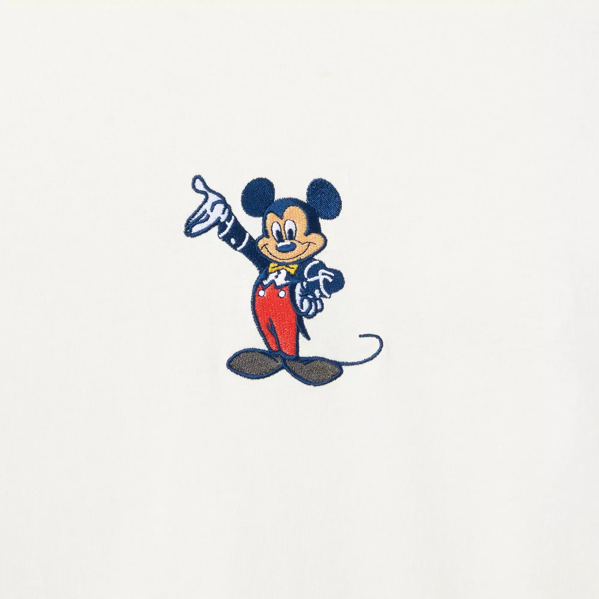 Cartoon mouse inspired by Mickey, wearing red pants and yellow shoes, smiling and pointing on a white background.