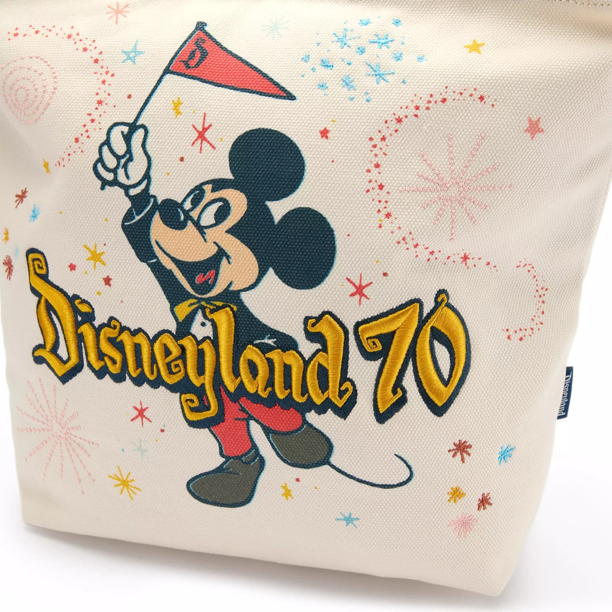 Mickey Mouse holds a red flag above text reading "Disneyland 70'" with colorful fireworks in the background.