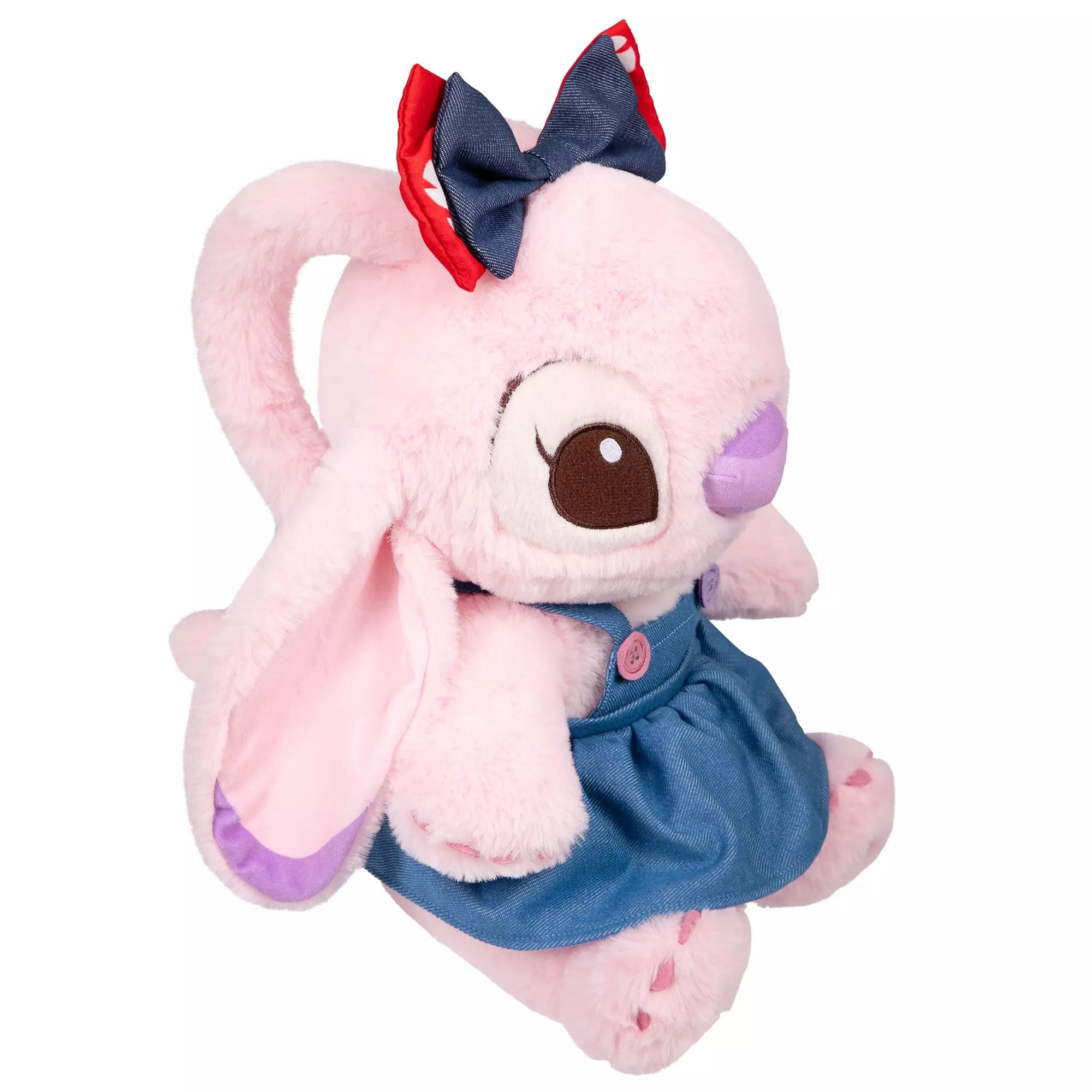 Plush pink bunny in a blue dress, like an Angel plush, with a red and blue bow, sitting upright and facing sideways.