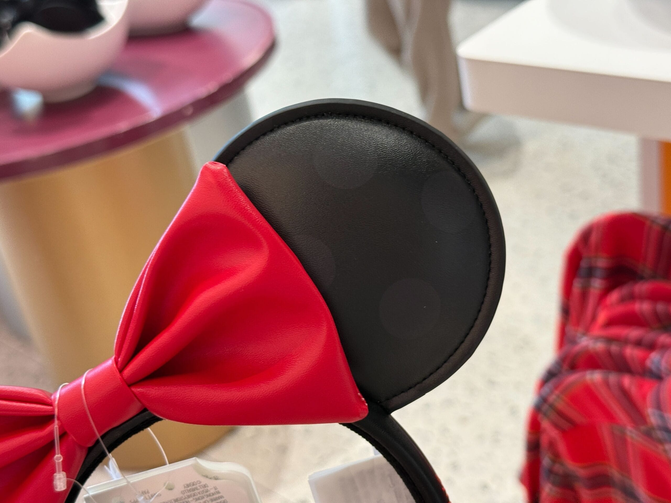 A close-up of a Minnie Mouse ear headband with a red bow, displayed at the Disneyland Resort store.