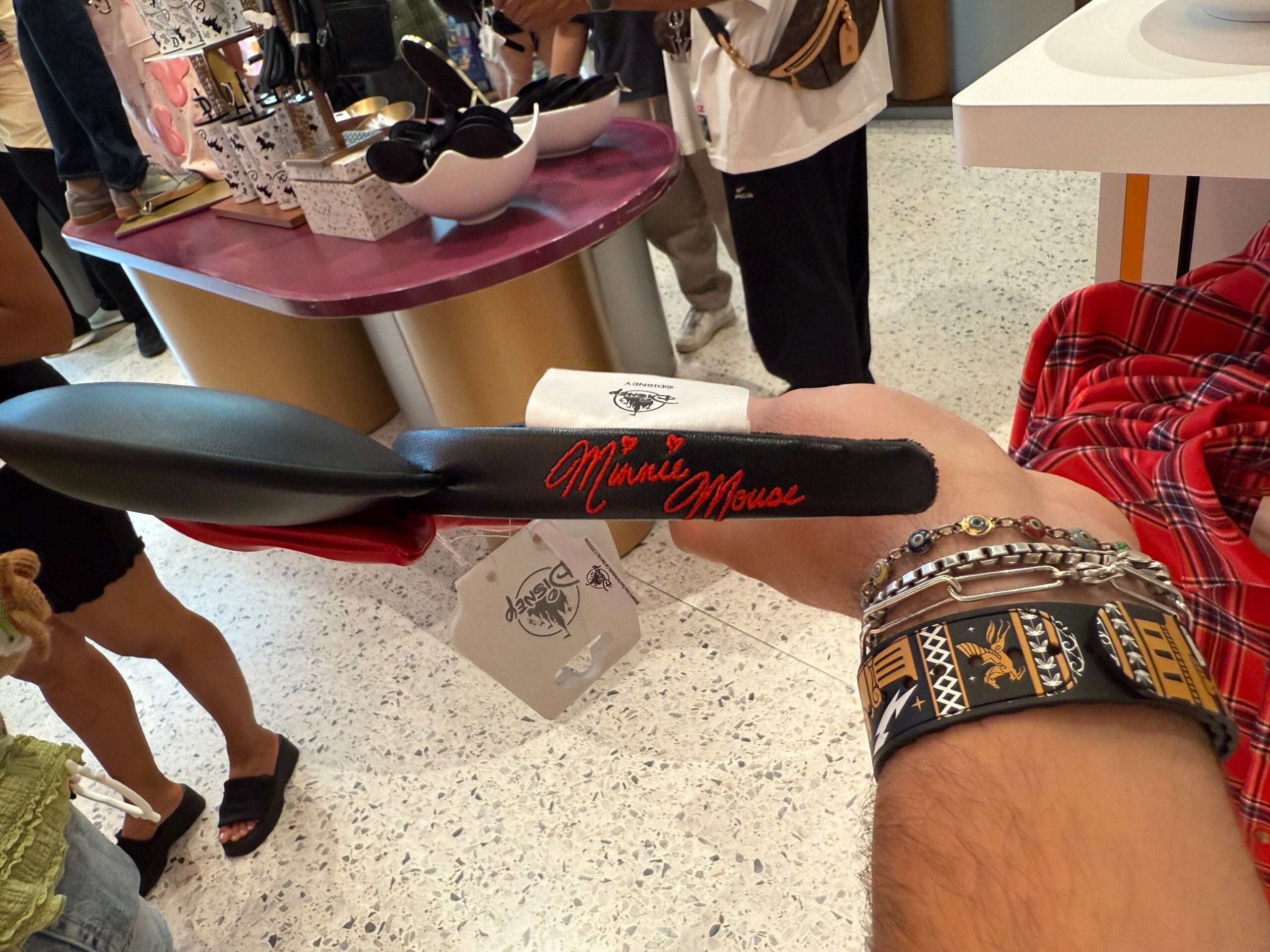 A person holds a black spatula with "Minnie Mouse" written in red at a Disneyland Resort store display.