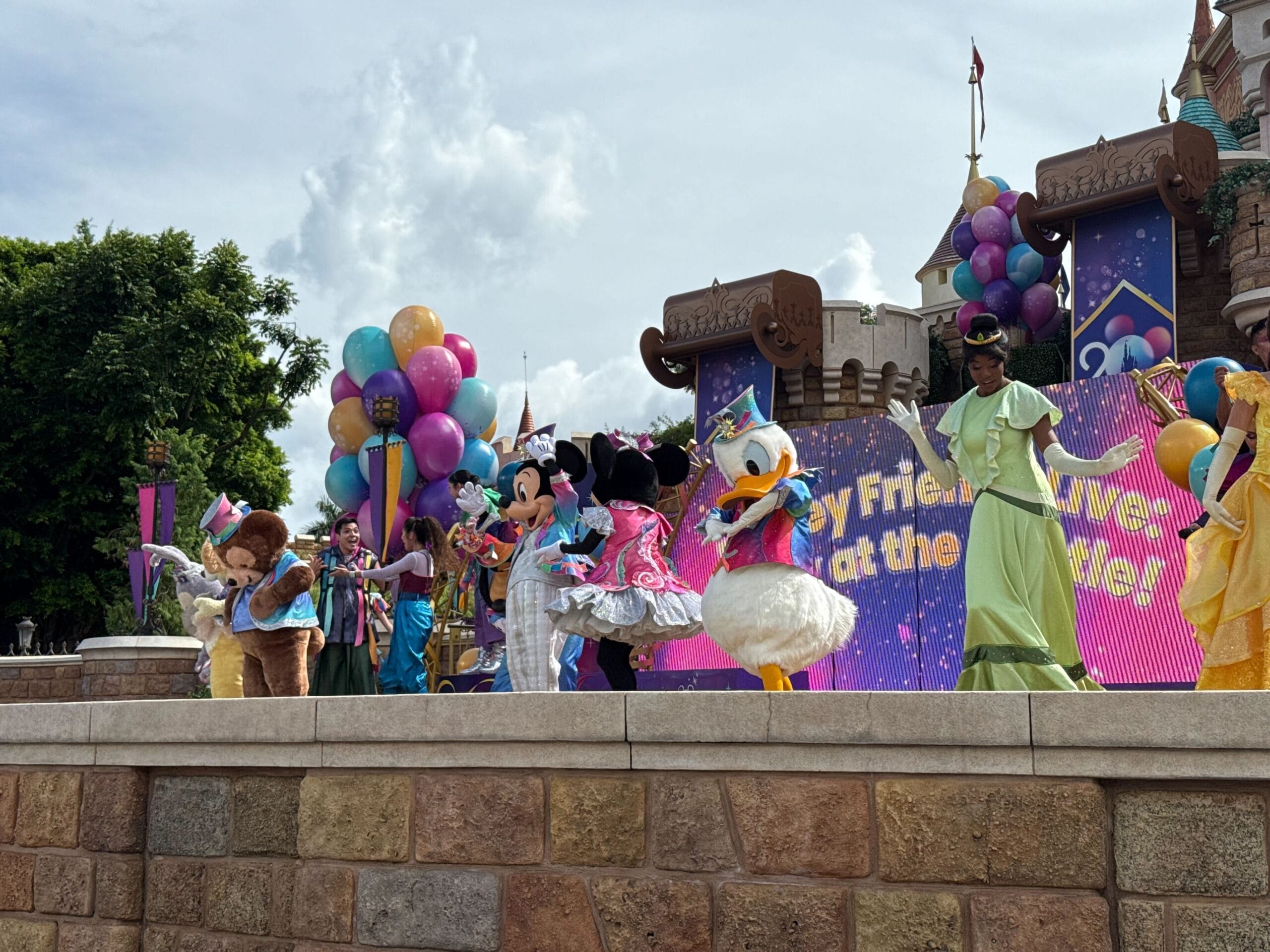 Disney Friends Live: Mickey, Minnie, and Daisy perform on stage at Hong Kong Disneyland with balloons and a castle backdrop.
