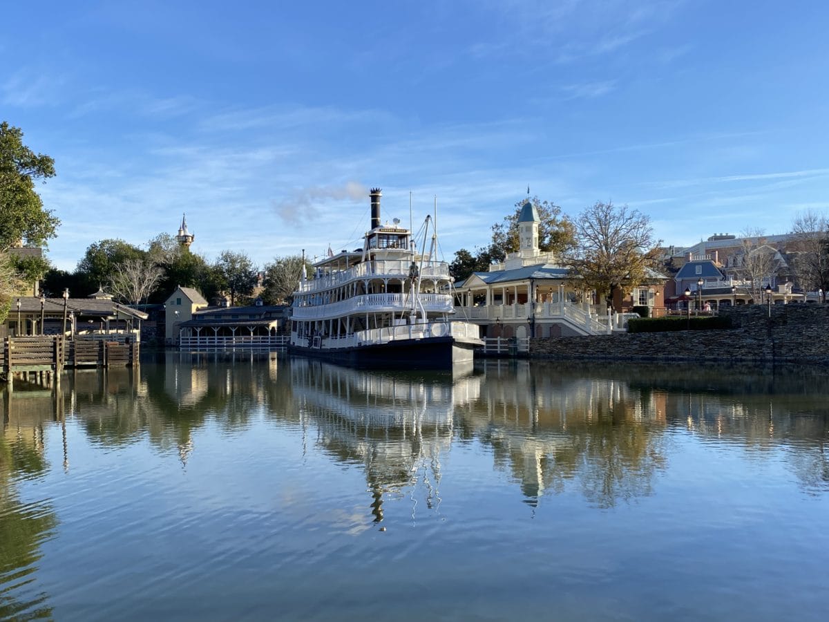 The Liberty Belle Riverboat - Liberty Square Riverboat Closing  near Tom Sawyer Island, with buildings and trees under a clear blue sky.