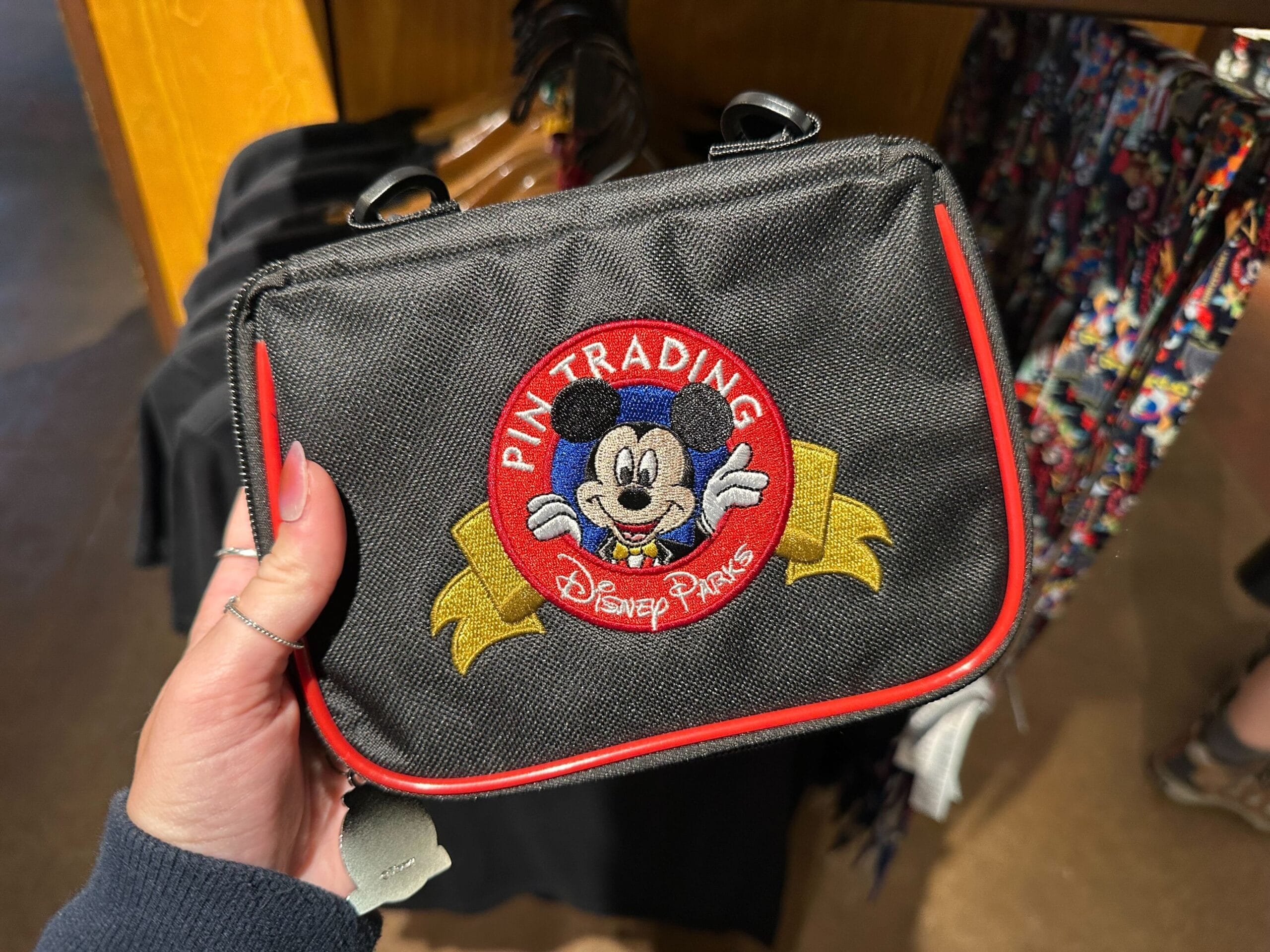 Hand holding a black Disney Parks bag with a "Pin Trading" Mickey patch—perfect for your WDWNT Summer Auction bid!