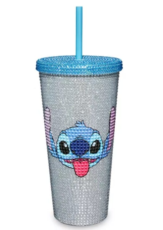 A silver rhinestone tumbler with a blue lid, blue straw, and Lilo & Stitch merchandise cartoon Stitch face on the front.
