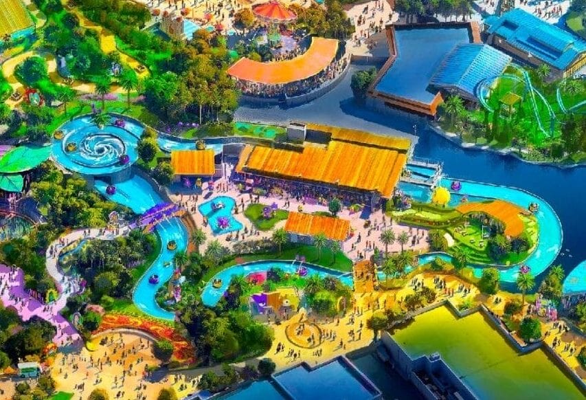 Aerial view of the colorful, illuminated Universal Kids Resort surrounded by trees and winding roads at night.