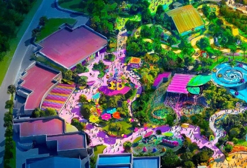 Aerial view of the colorful, illuminated Universal Kids Resort surrounded by trees and winding roads at night.
