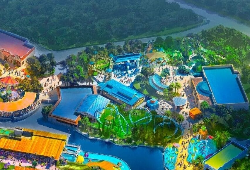 Aerial view of the brightly colored, illuminated Universal Kids Resort theme park surrounded by trees and winding roads at night.