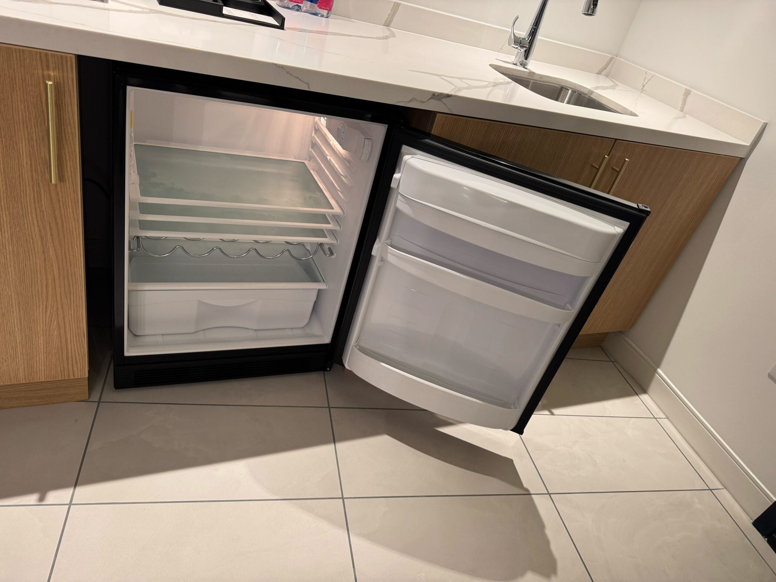 An open mini fridge and freezer built into a kitchen cabinet in the Celestial Suite at Universal Helios Grand Hotel.