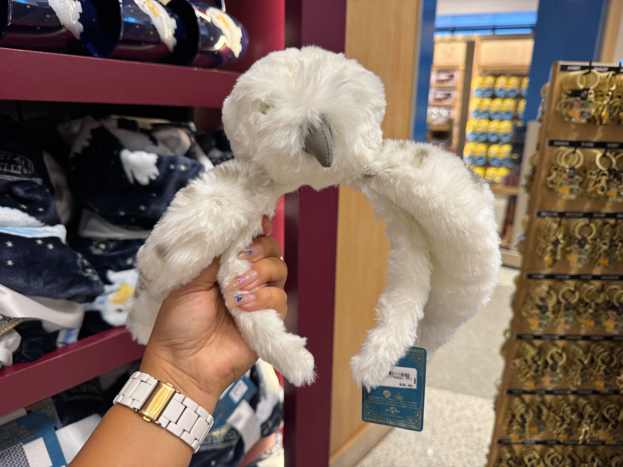 Hand holding a white plush headband shaped like Hedwig, perfect for Harry Potter fans still waiting for their letter.