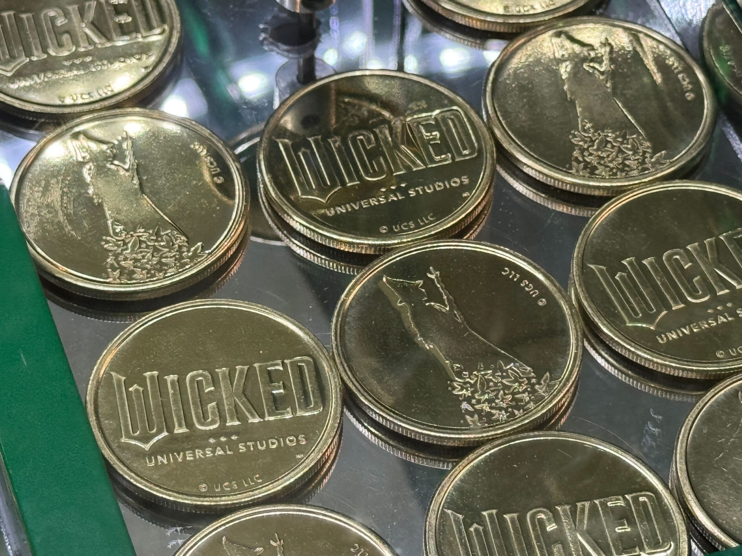 Wicked collectible medallions featuring a witch and "WICKED" design, displayed at Universal Studios Florida.